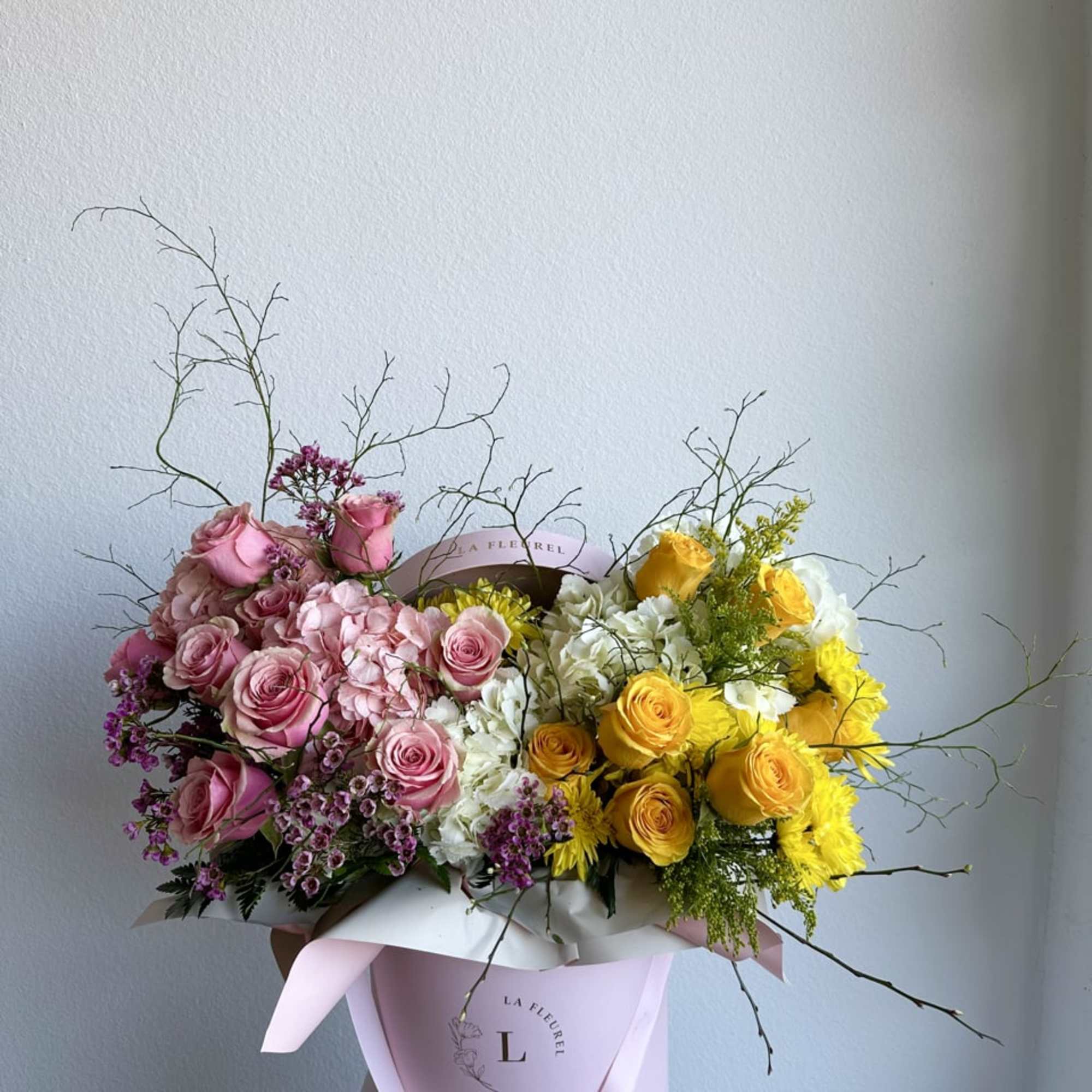 This beautiful arrangement is filled with yellow and pink roses, hydrangeas, and