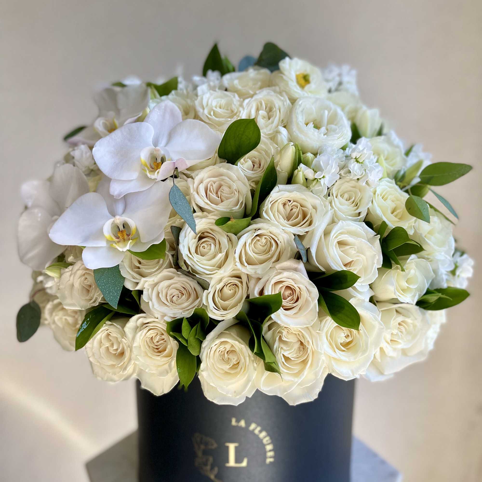This beautiful arrangement is filled with white roses, tulips and orchids to