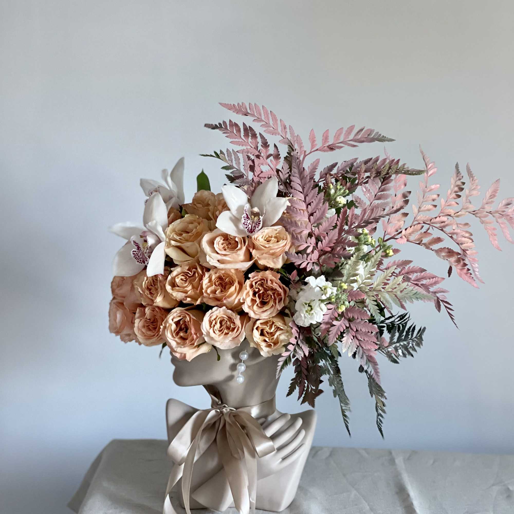 This beautiful arrangement is filled with peach roses, orchids and greens to