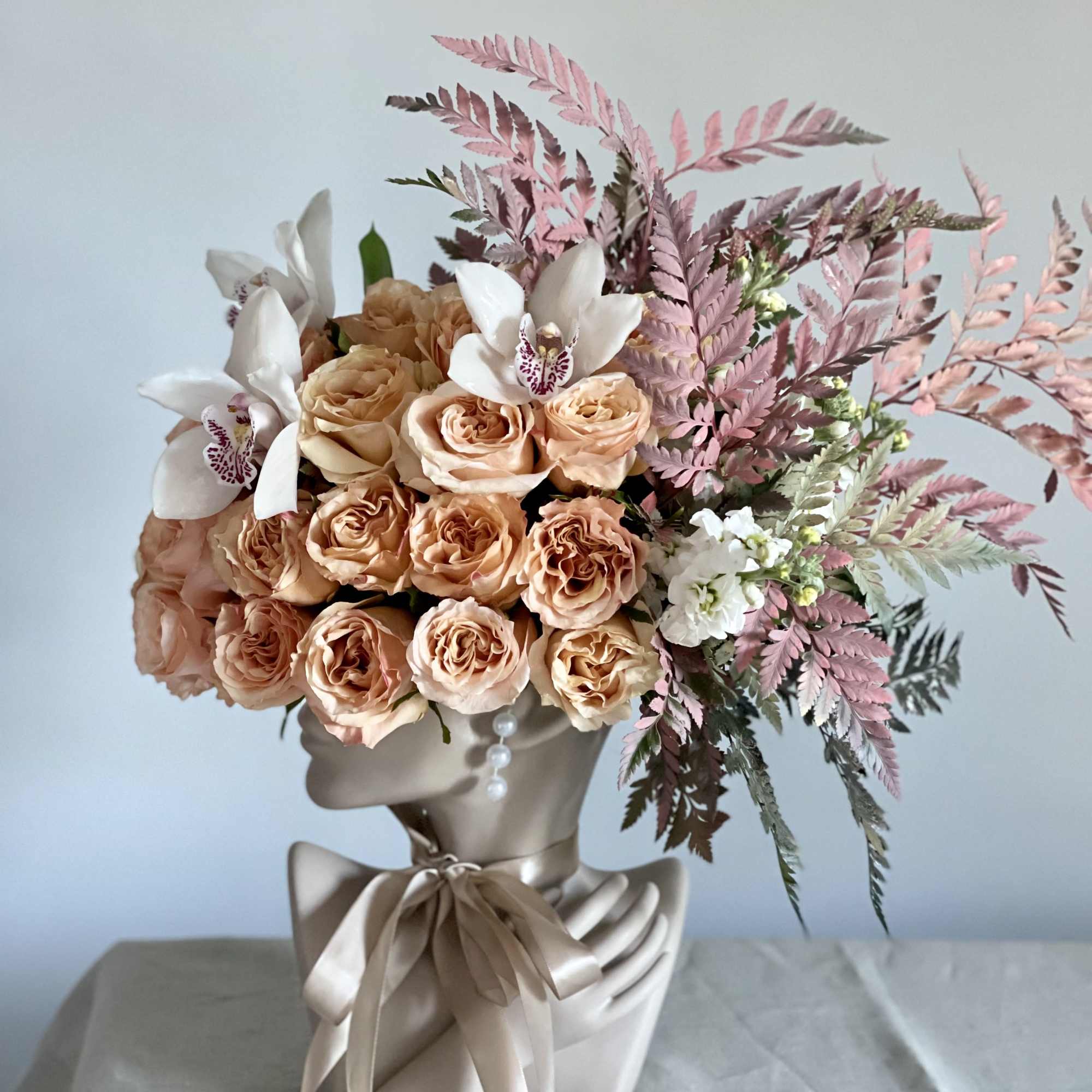 This beautiful arrangement is filled with peach roses, orchids and greens to