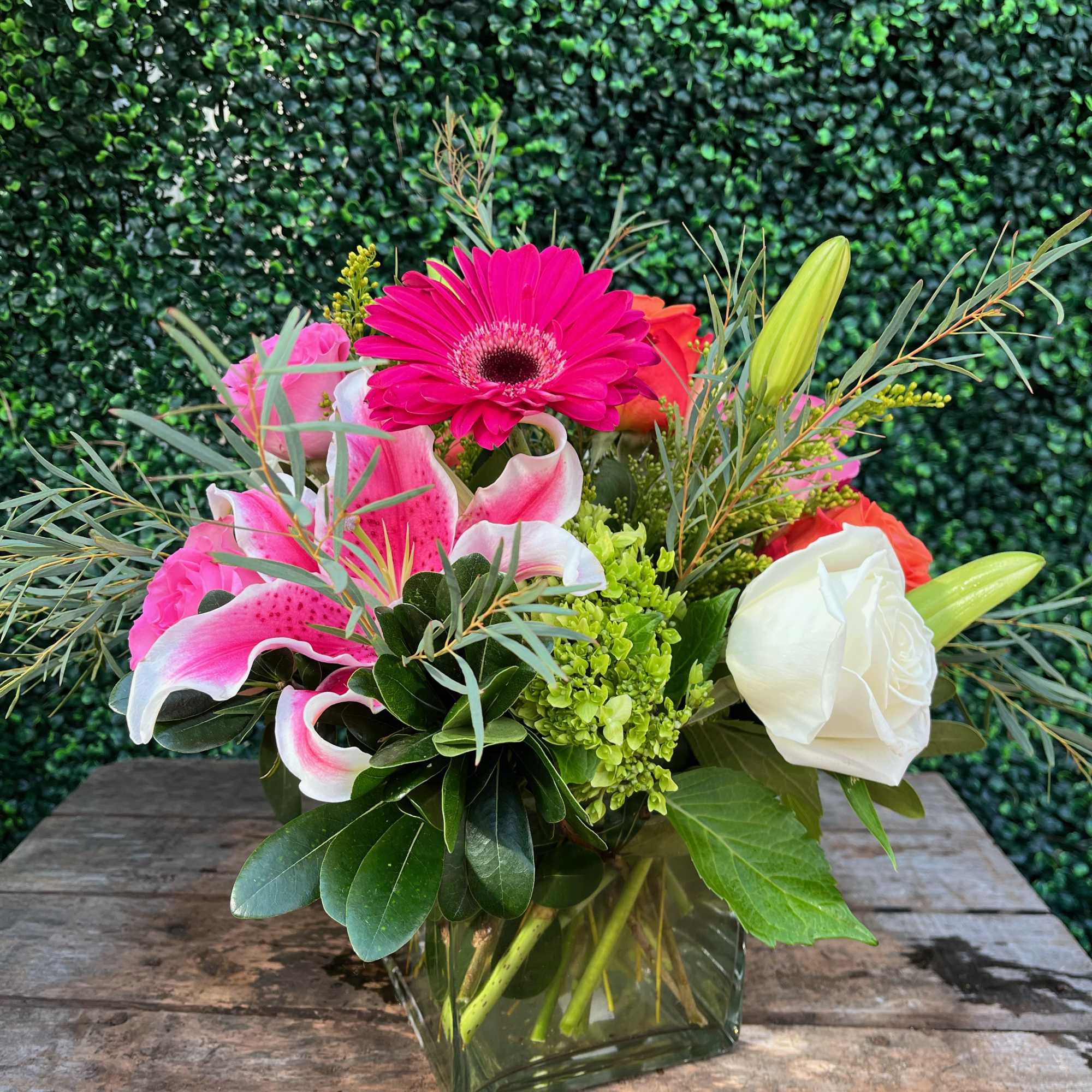 Tropical Sunset is in a cube vase. It includes 6-8 roses, lilies