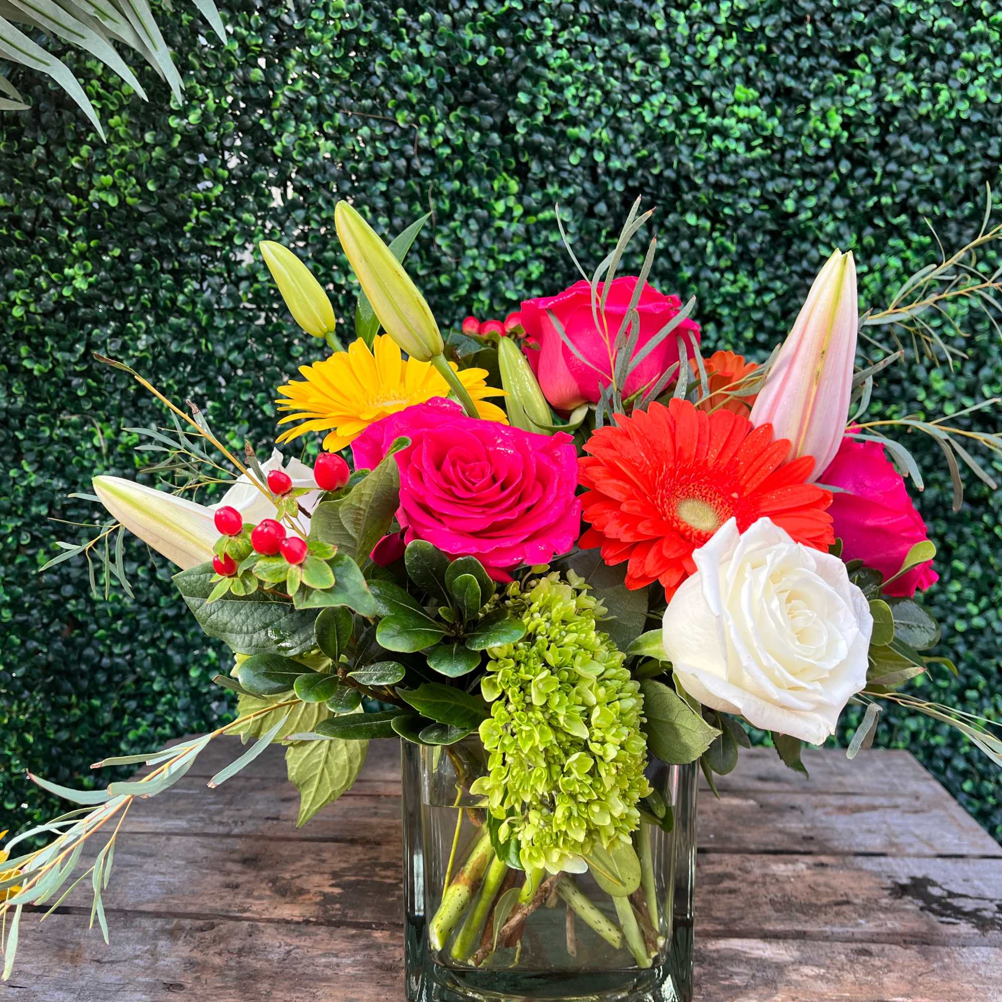 Tropical Sunset is in a cube vase. It includes 6-8 roses, lilies