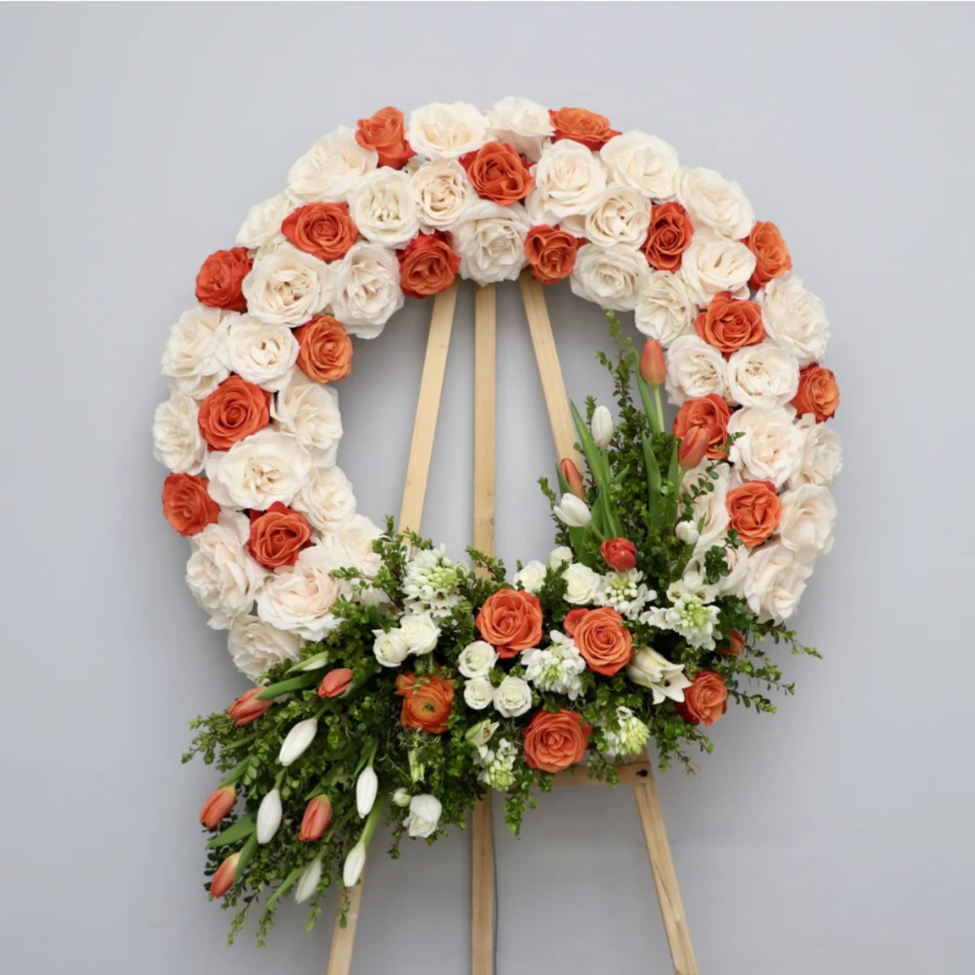 This wreath is made with creamy white roses and touches of orange