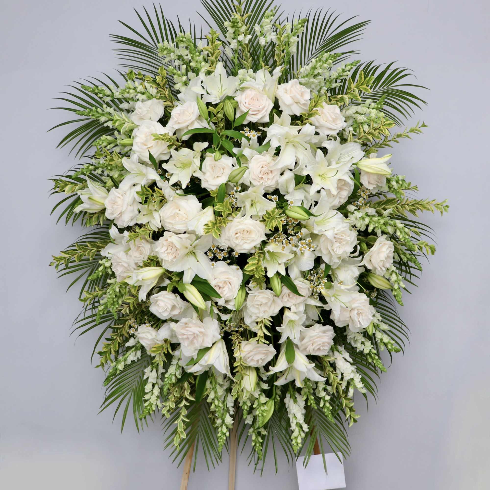 White spray filled with lilies, roses, and snapdragons. 

We include easel, printed