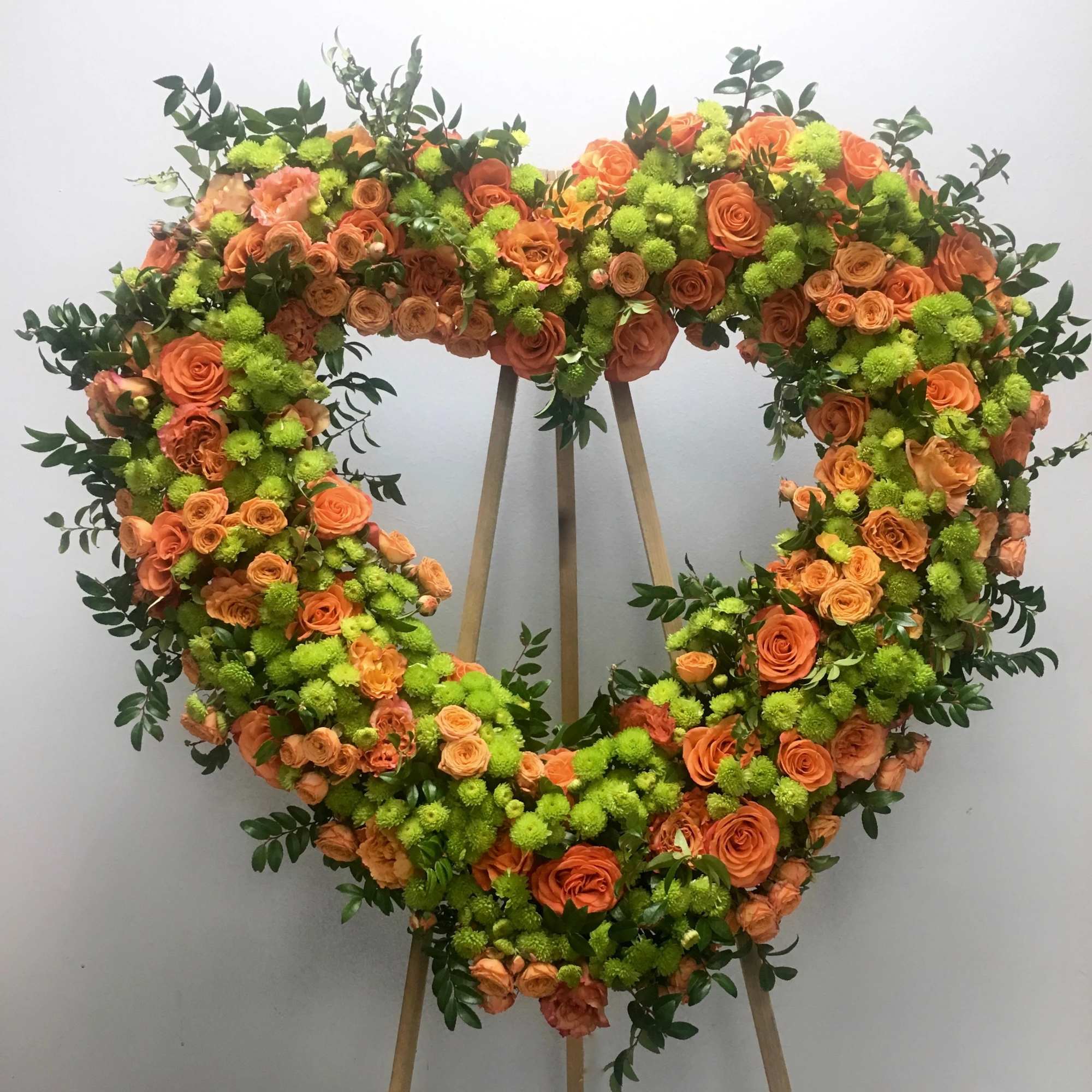 &quot;This heart mixes an array of orange roses and seasonal greens to