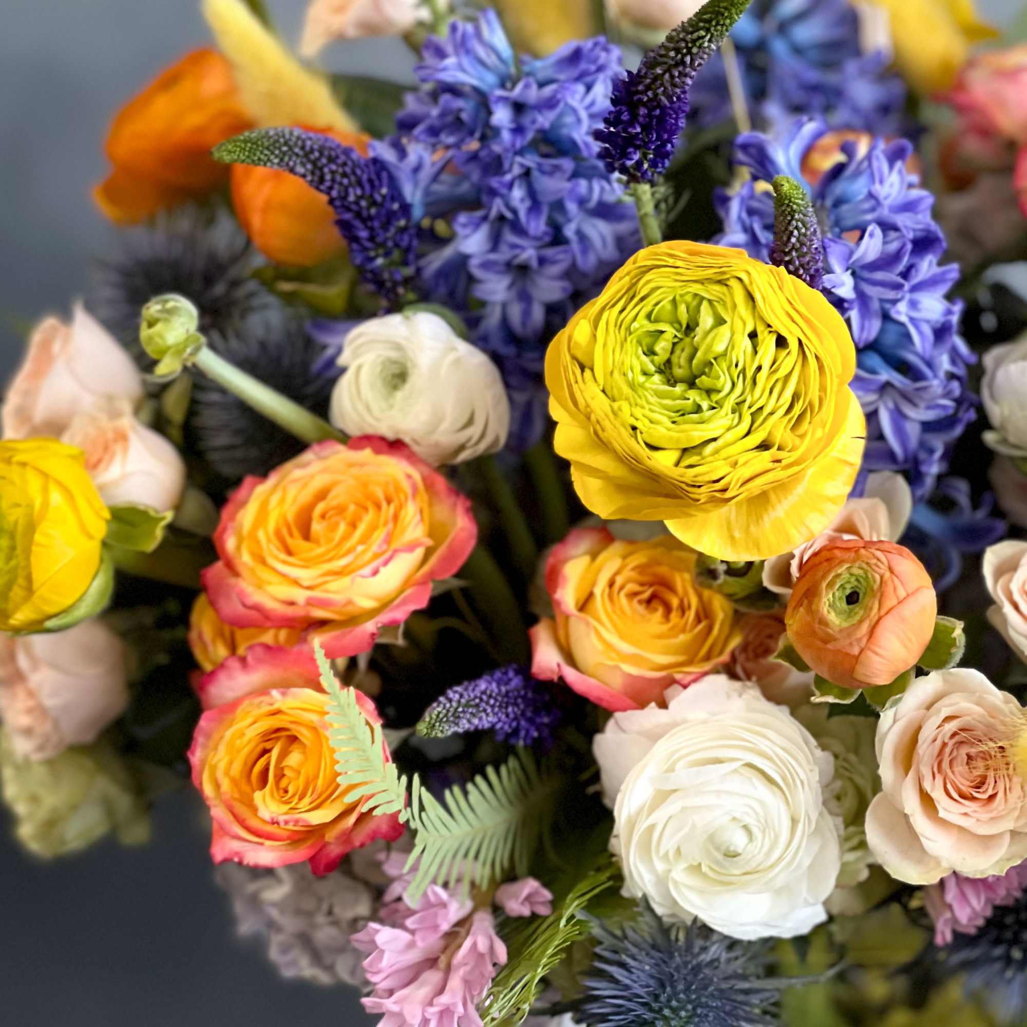 The design features elegant splashes of yellow ranunculus, orange, peach and white