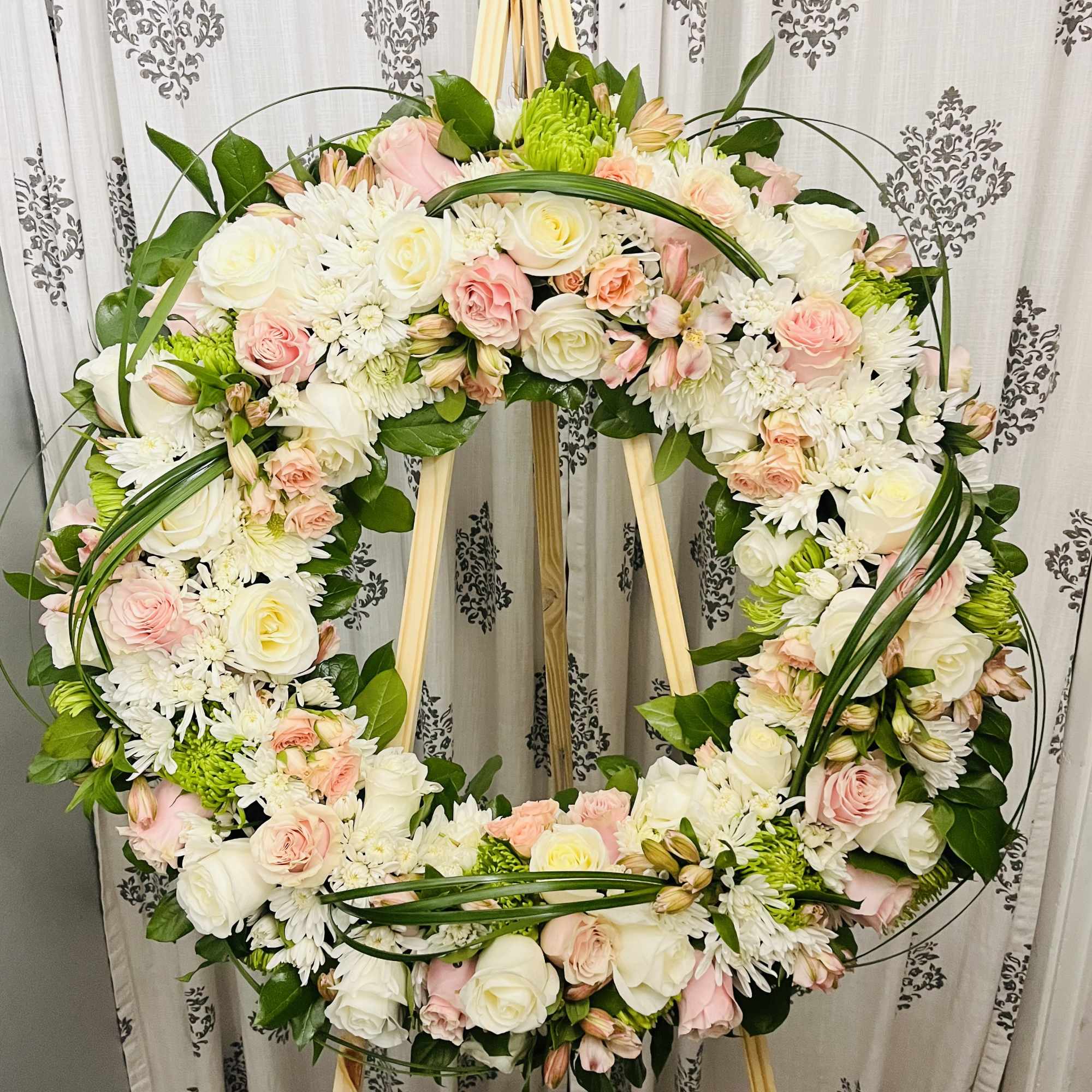 This gentle Tribute wreath using, soft whites, pinks and spring greens, is