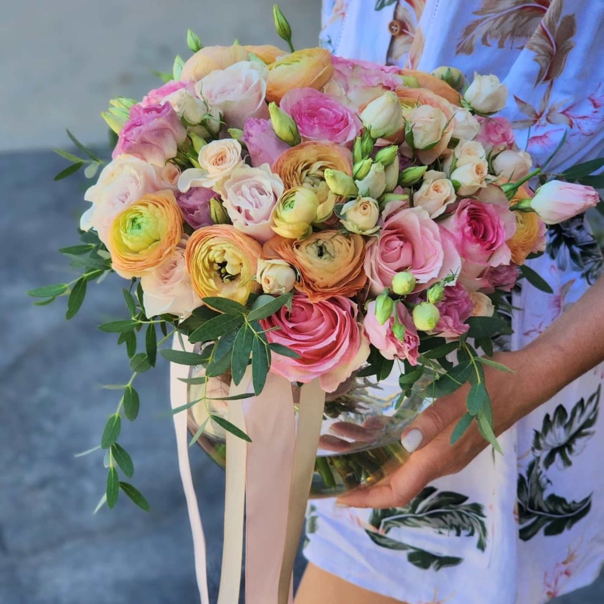  A clear vase arrangement featuring peach Ranunculus, pink roses , and