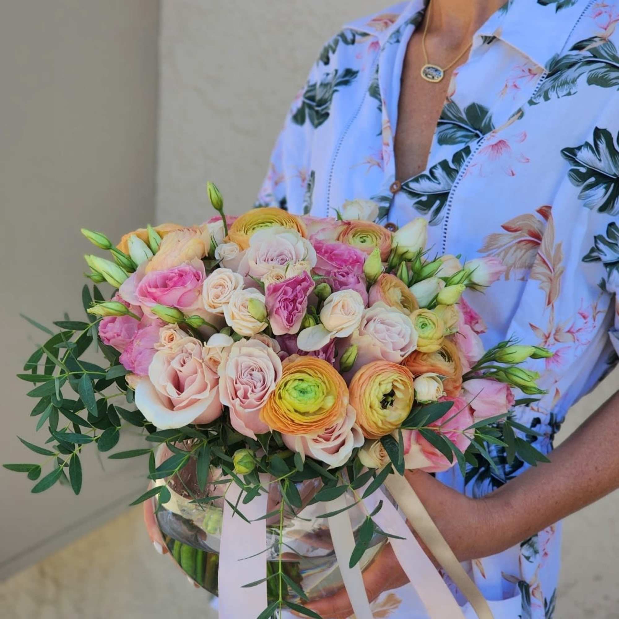  A clear vase arrangement featuring peach Ranunculus, pink roses , and