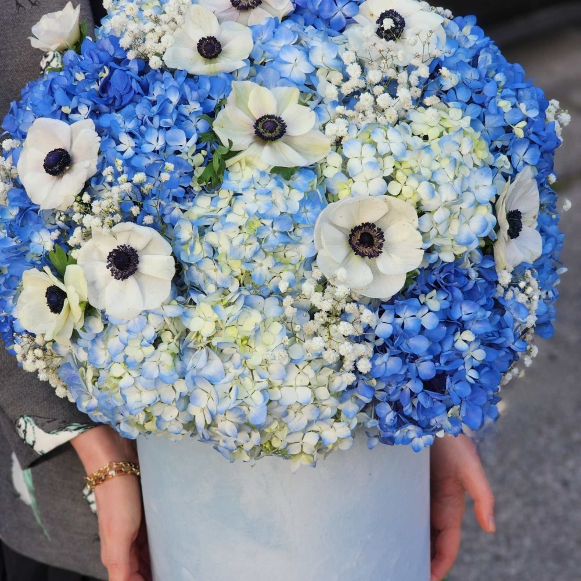 Stunning blue hydrangeas complemented by delicate anemones, all presented in an elegant