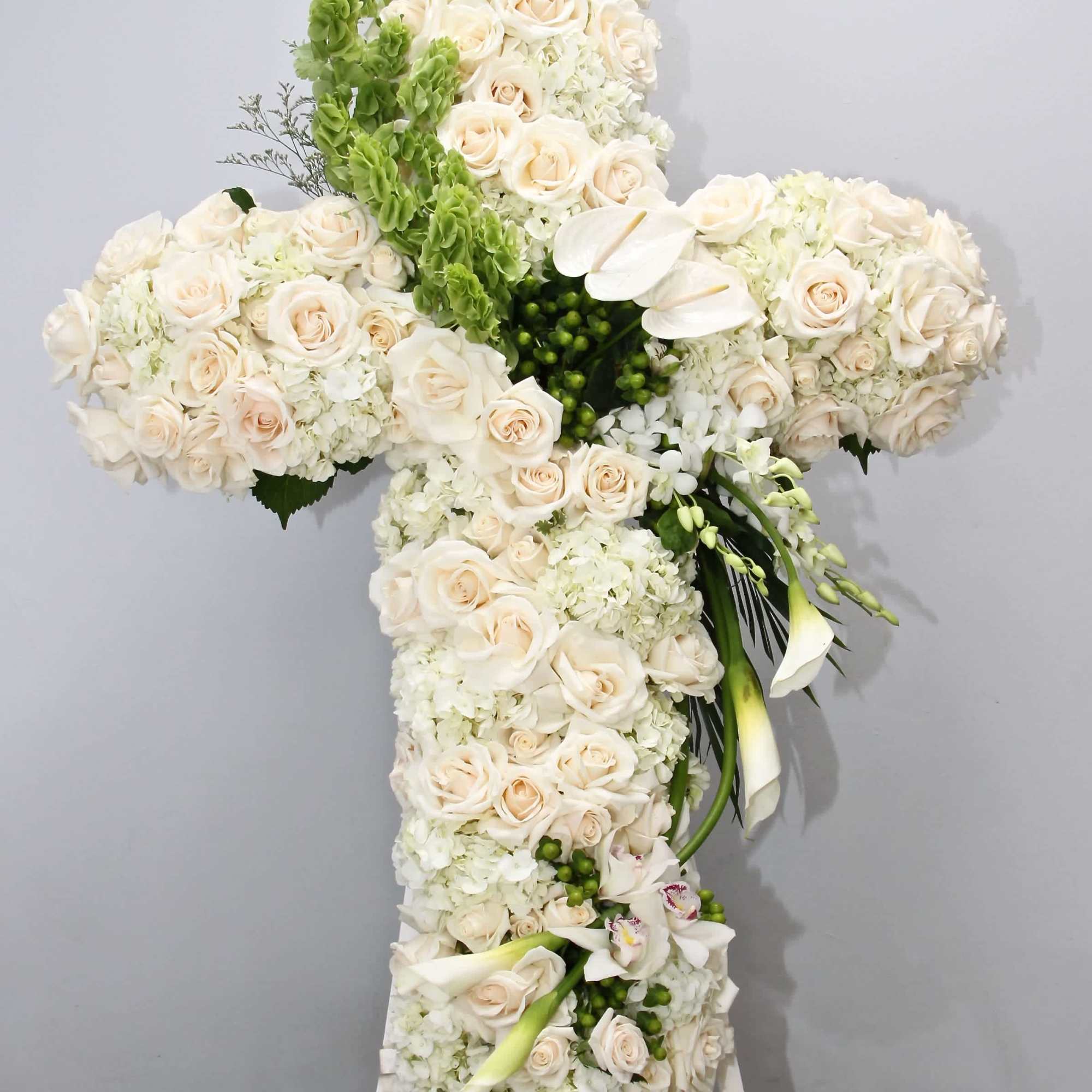 This beautiful sympathy cross includes fluffy hydrangeas, roses, lilies and seasonal greens.