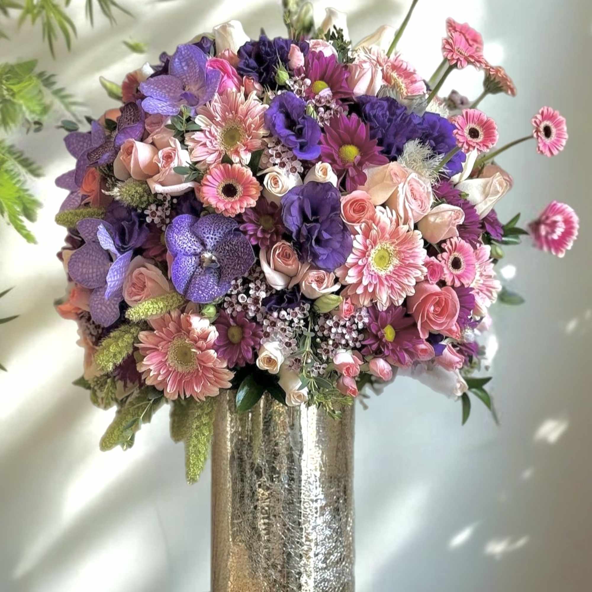 The arrangement features a variety of vibrant flowers, including roses,orchids, lilies, and