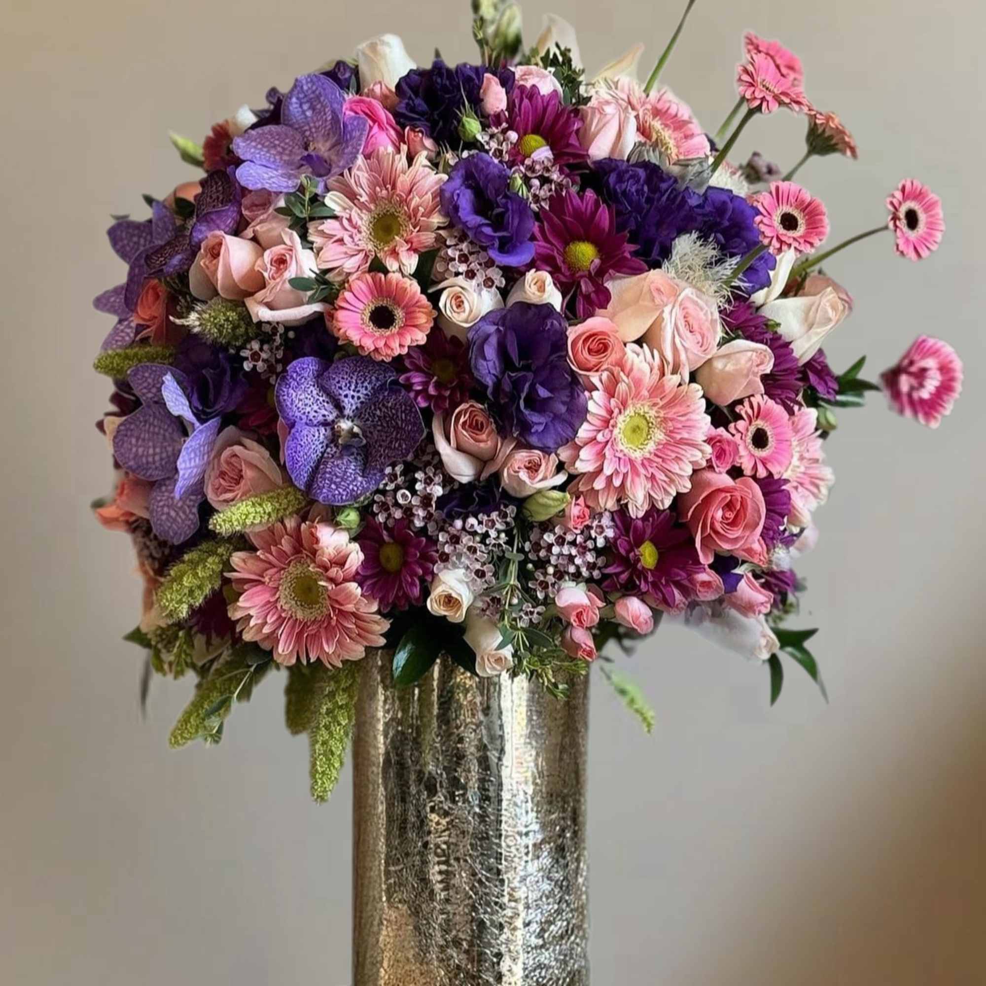 The arrangement features a variety of vibrant flowers, including roses,orchids, lilies, and