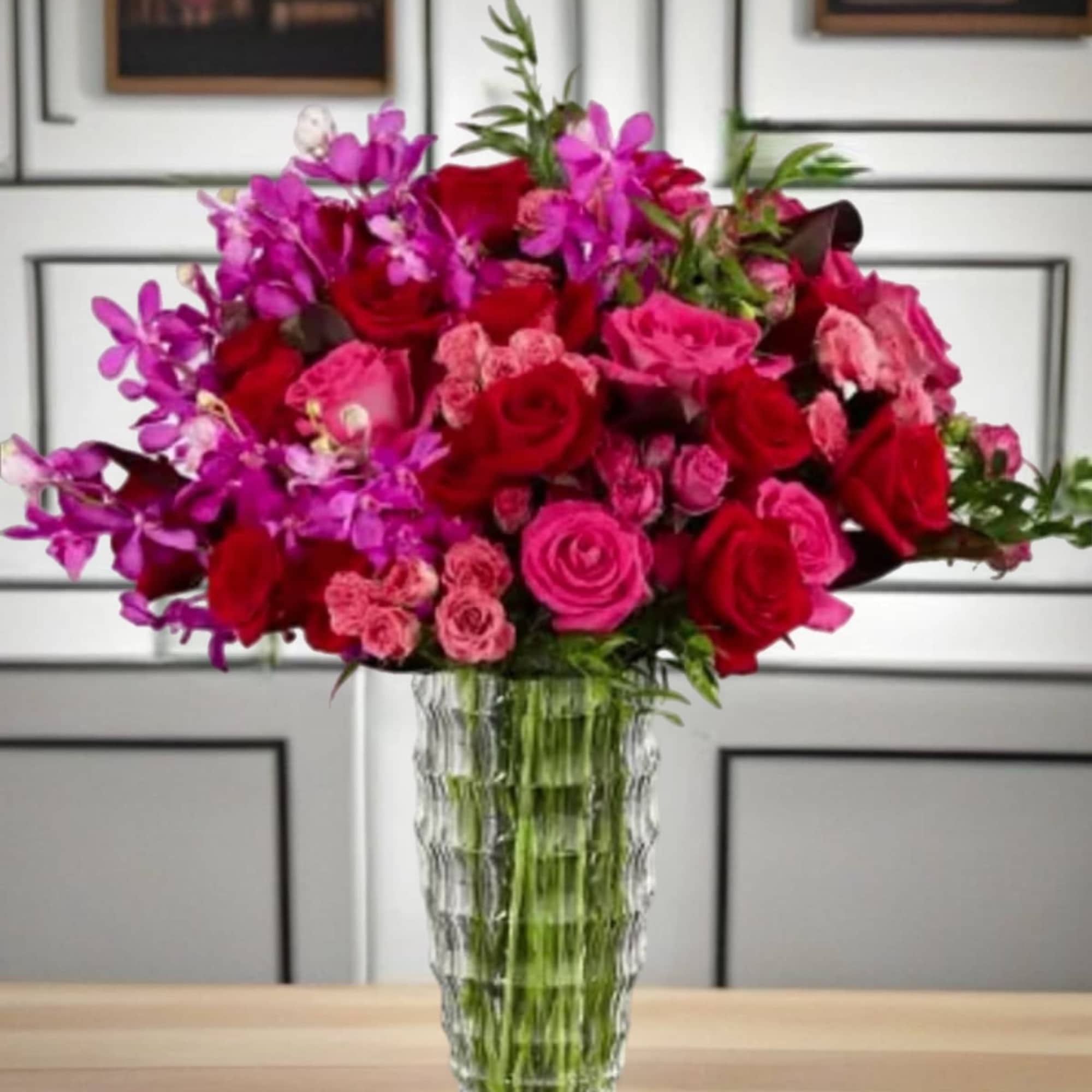 This vibrant arrangement of roses, tulips, and orchids is bursting with shades