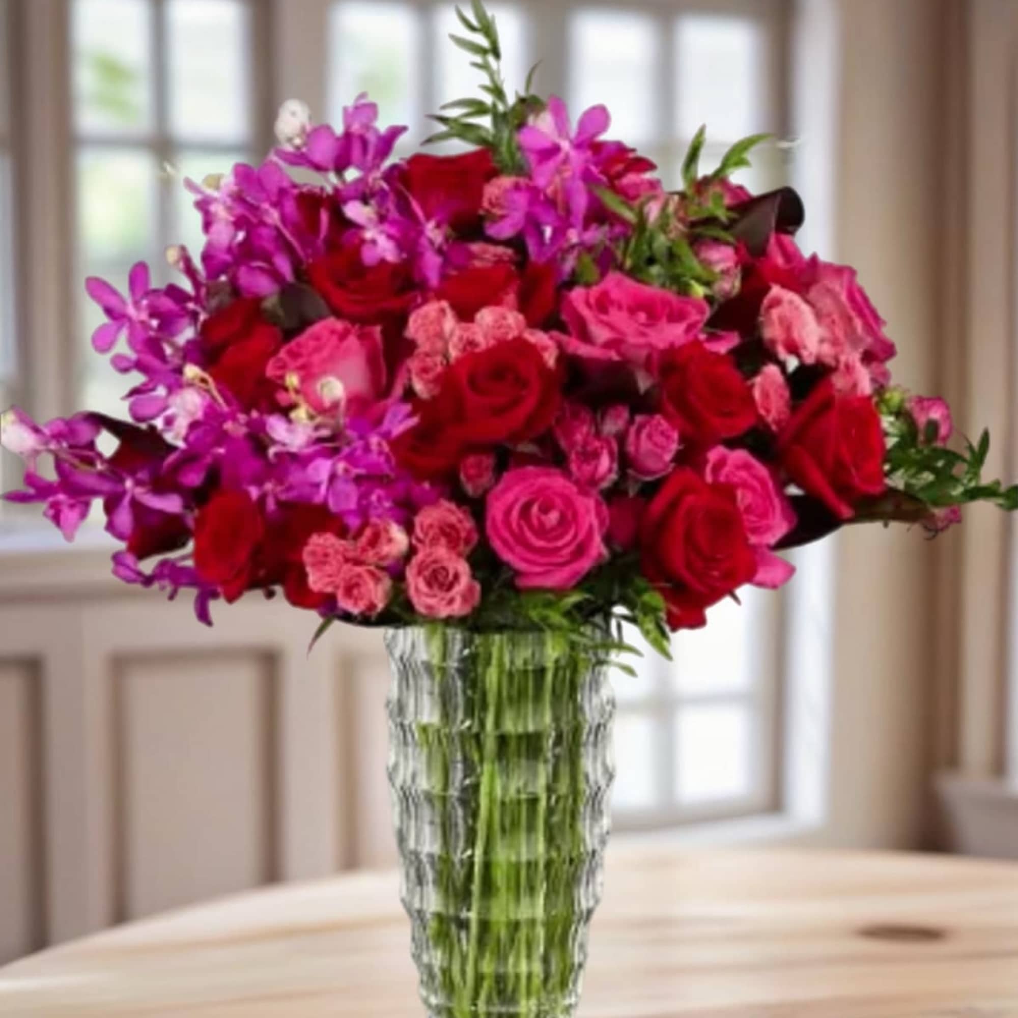 This vibrant arrangement of roses, tulips, and orchids is bursting with shades