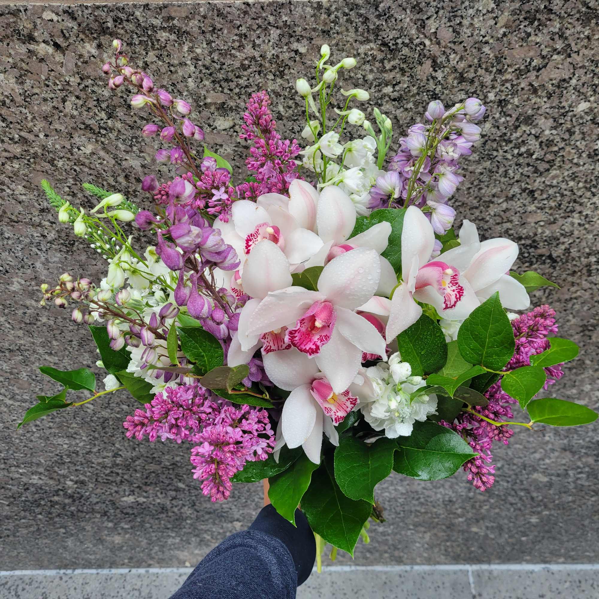 Lavender Lace Bouquet: Featuring white cymbidium orchids, hydrangeas, lilac, and stock, this