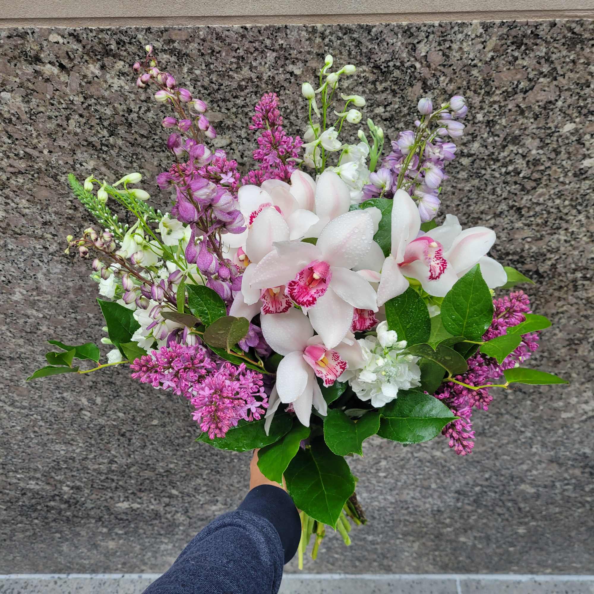Lavender Lace Bouquet: Featuring white cymbidium orchids, hydrangeas, lilac, and stock, this