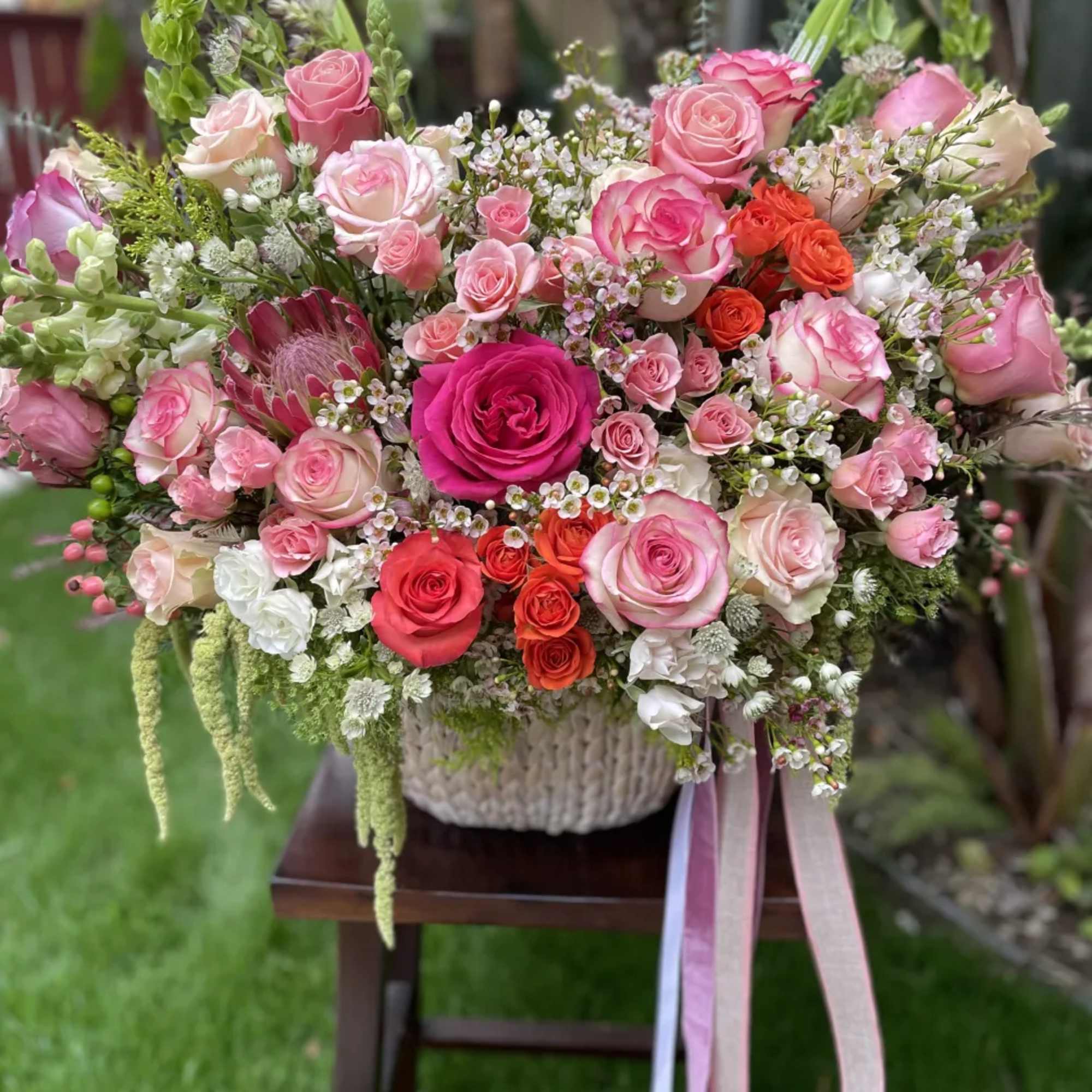 A magnificent French basket arrangement of oversized pink and peach-colored roses is