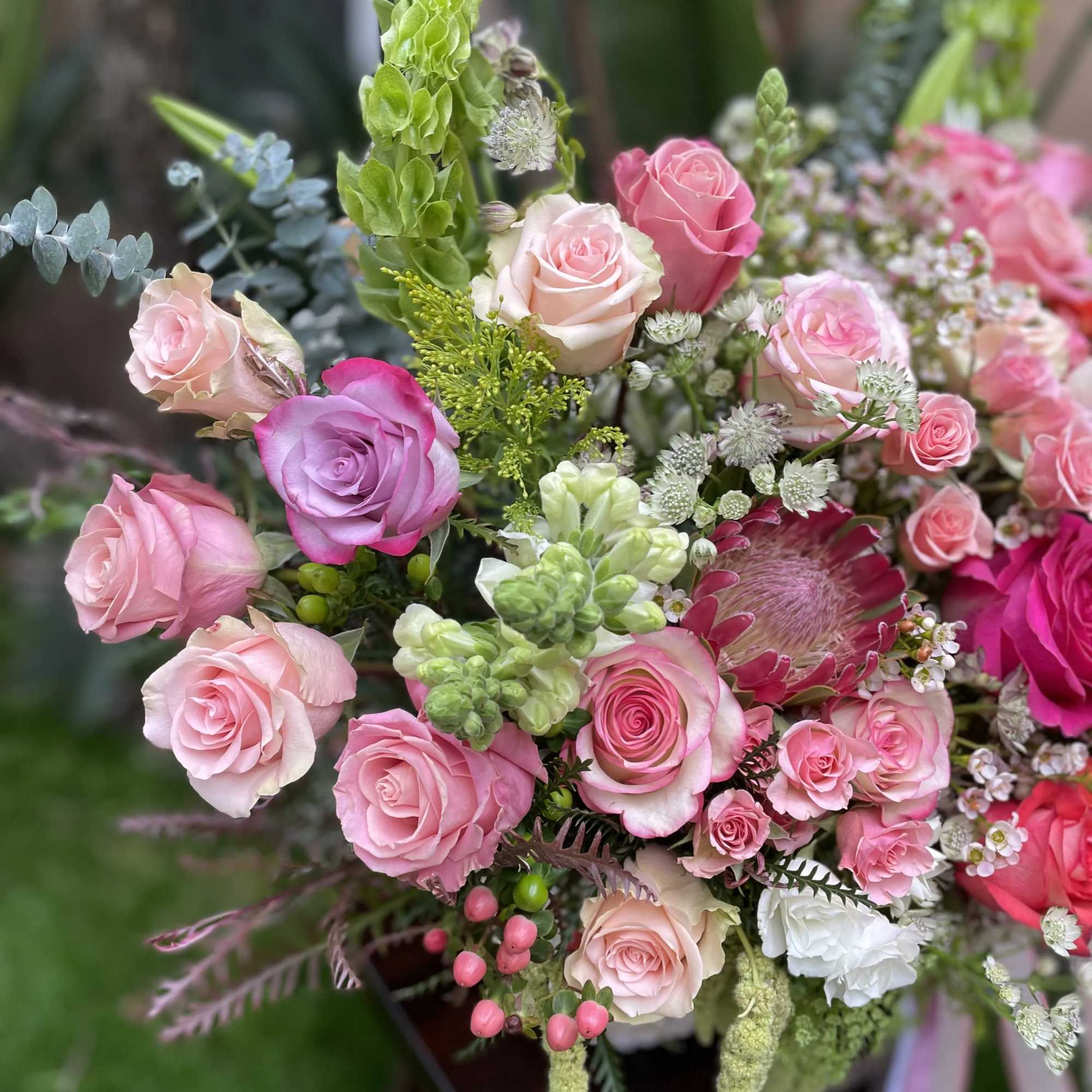 A magnificent French basket arrangement of oversized pink and peach-colored roses is