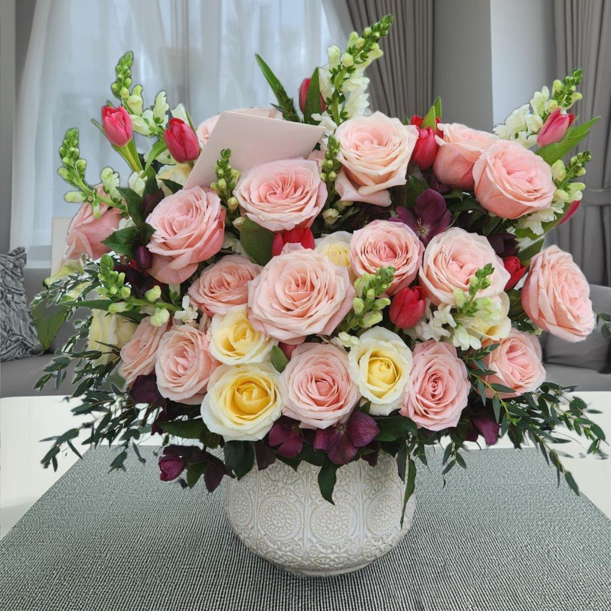 This stunning floral arrangement in a ceramic vase features of pink roses