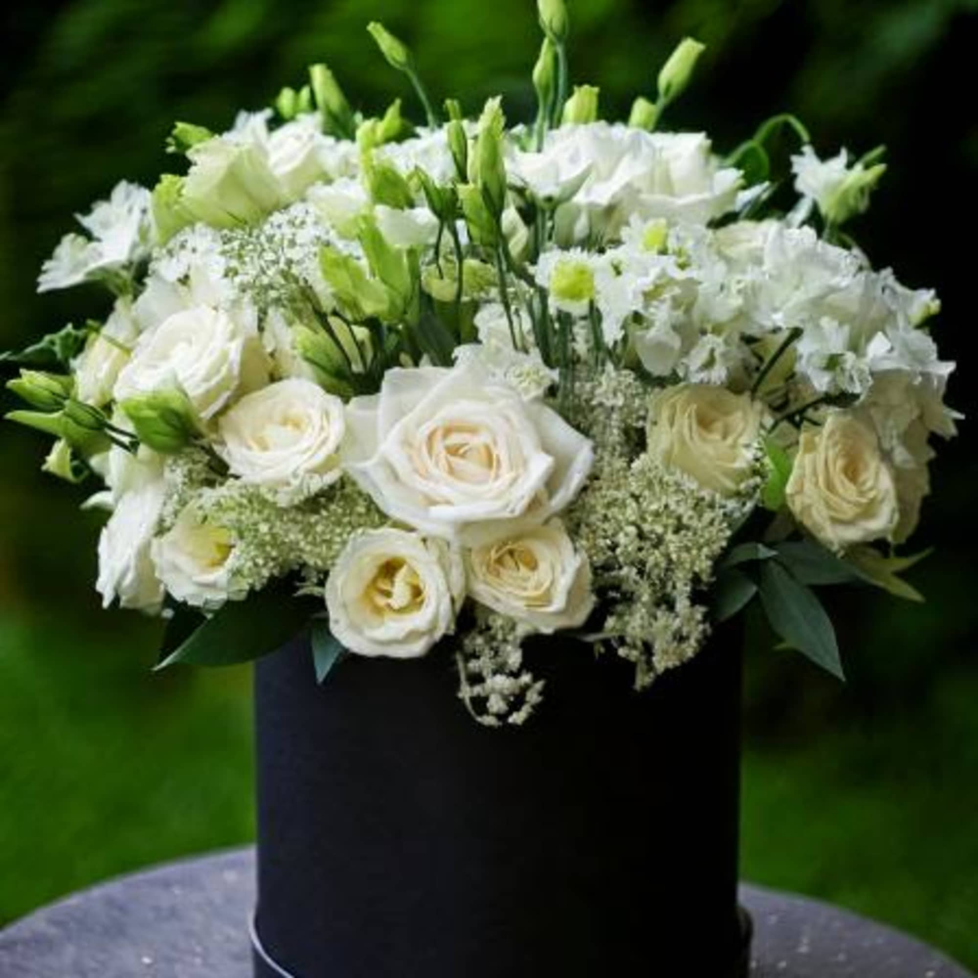 This elegant floral arrangement features a luxurious blend of white roses, delicate