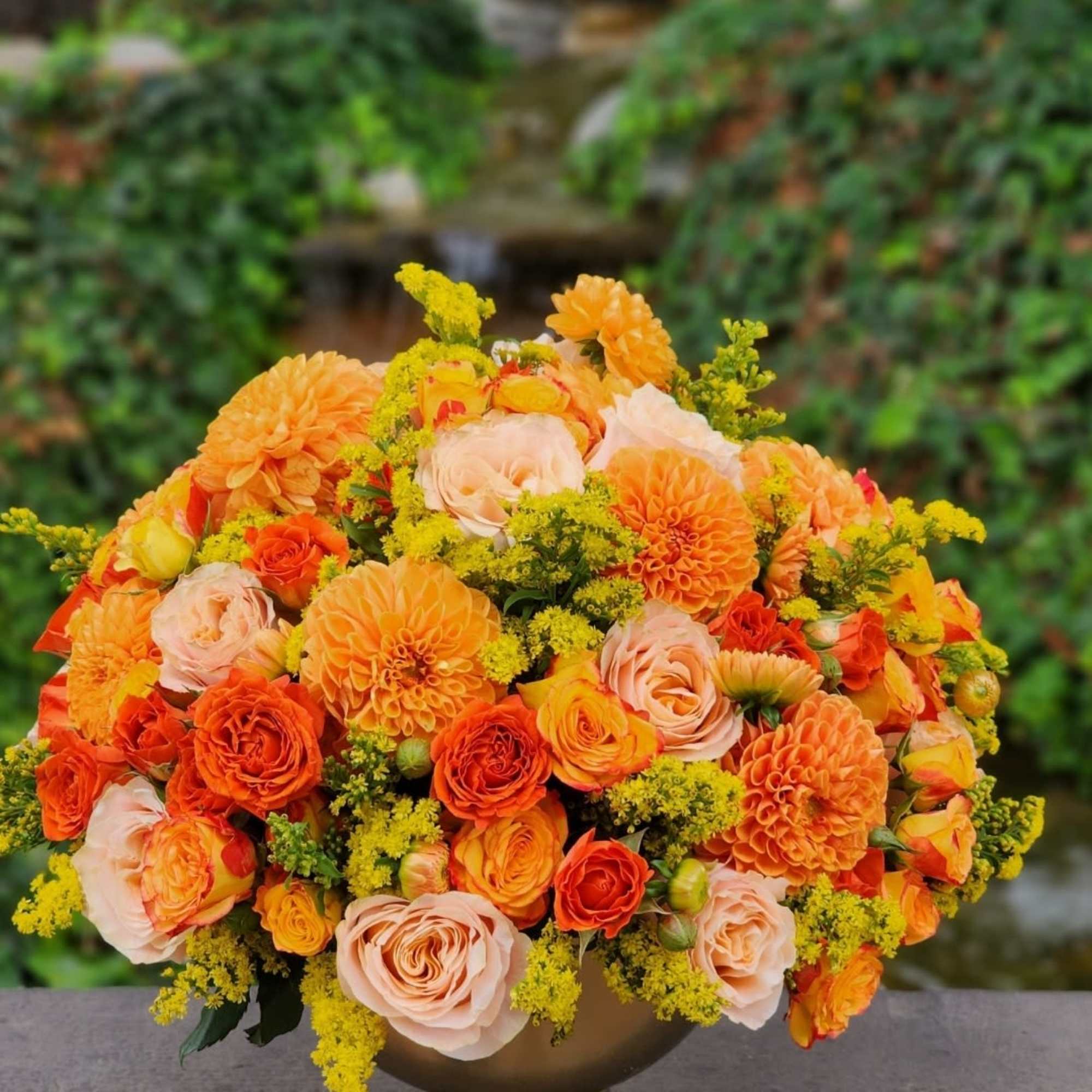 Celebrate autumn with this vibrant arrangement of orange dahlias, roses, and yellow