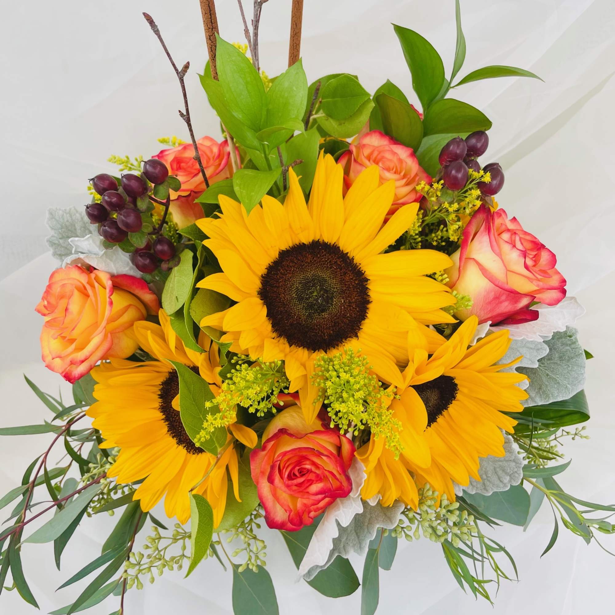 An assortment of roses and sunflowers with touches of fall!