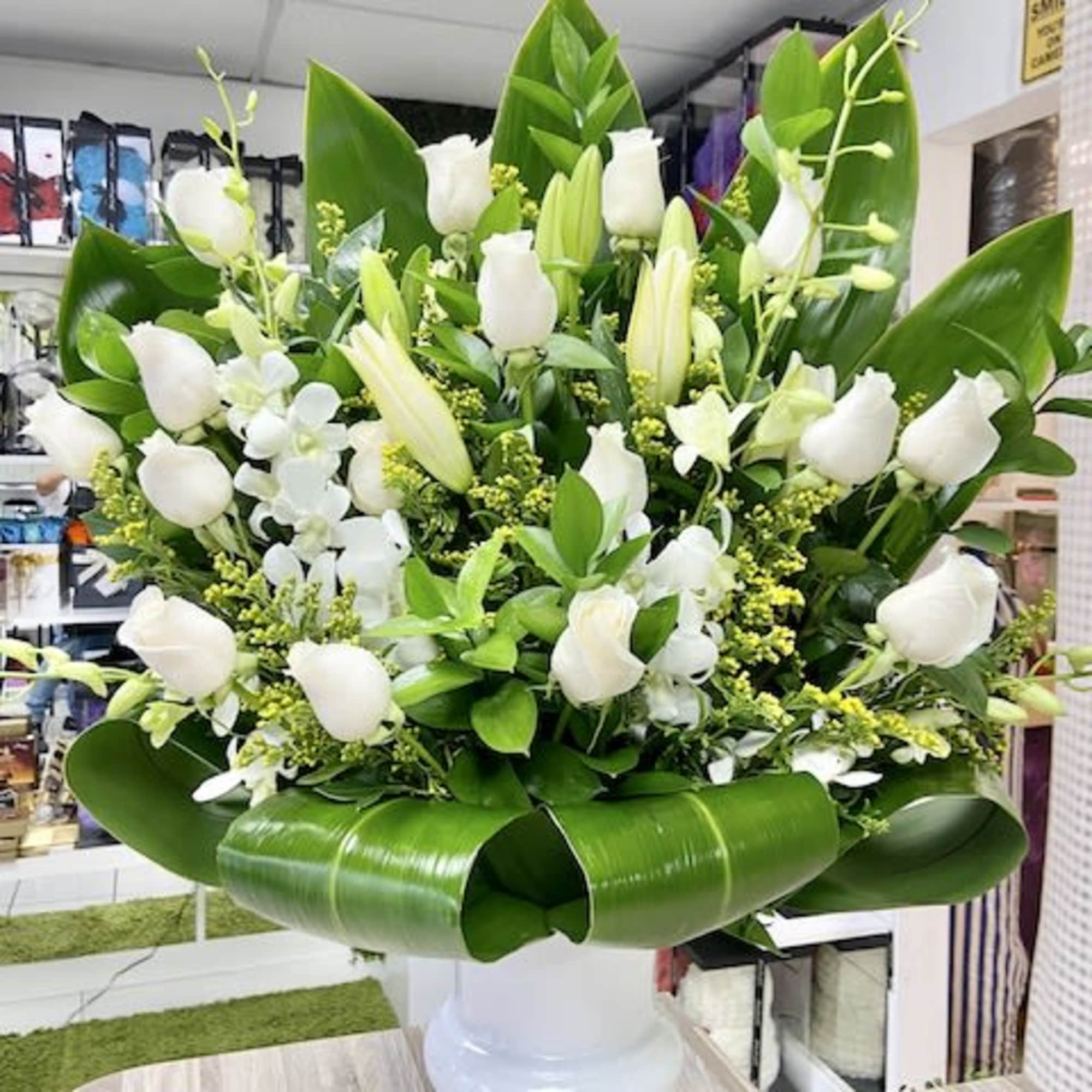 Tribute Funeral Flower Arrangement: Created with white lilies, roses, ruscus, greens, placed