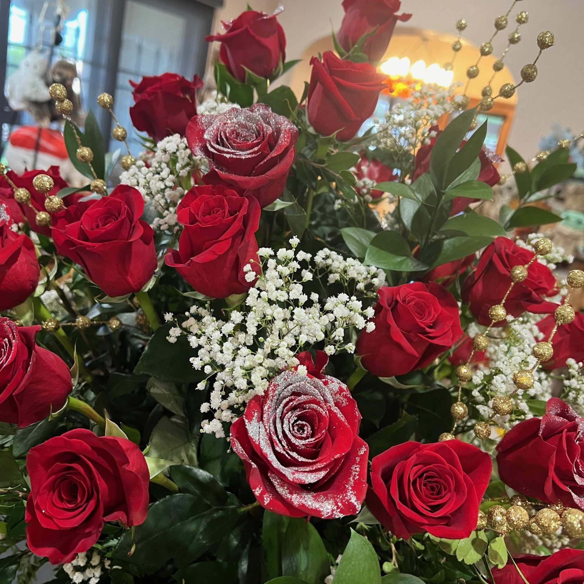 Red roses arranged inside a tall red box. glitters are added to