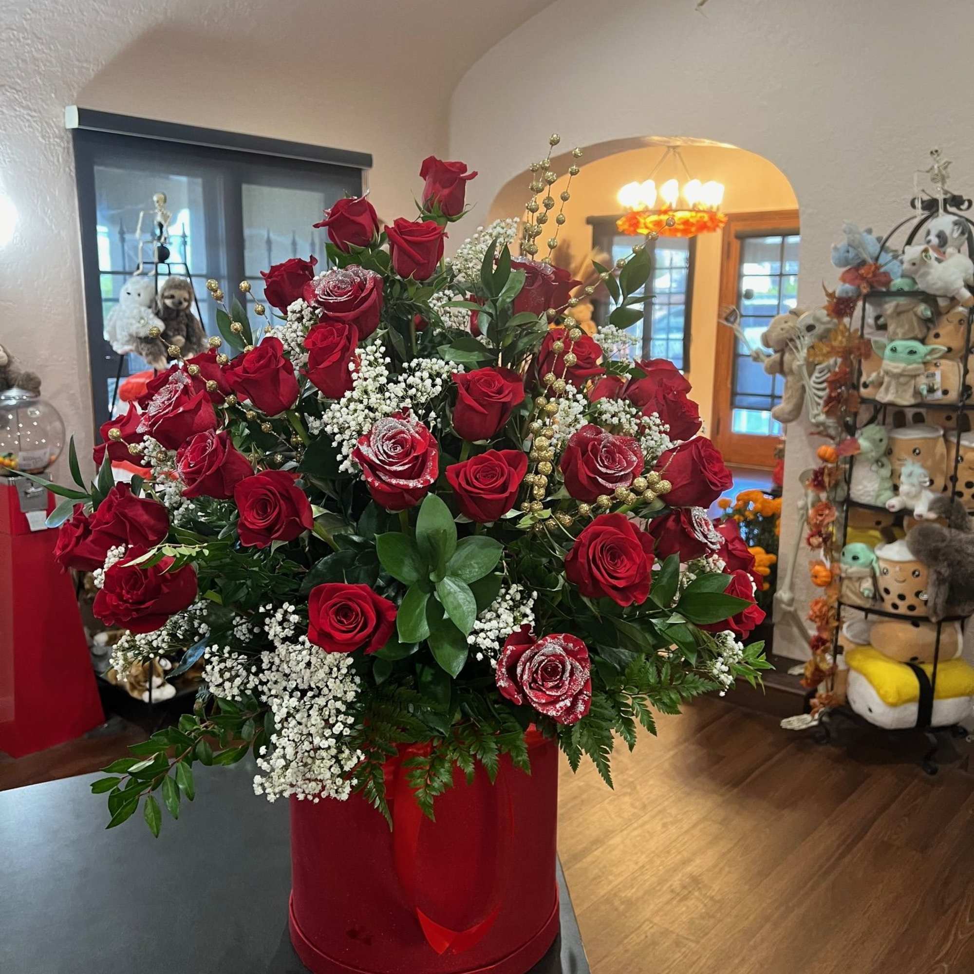 Red roses arranged inside a tall red box. glitters are added to