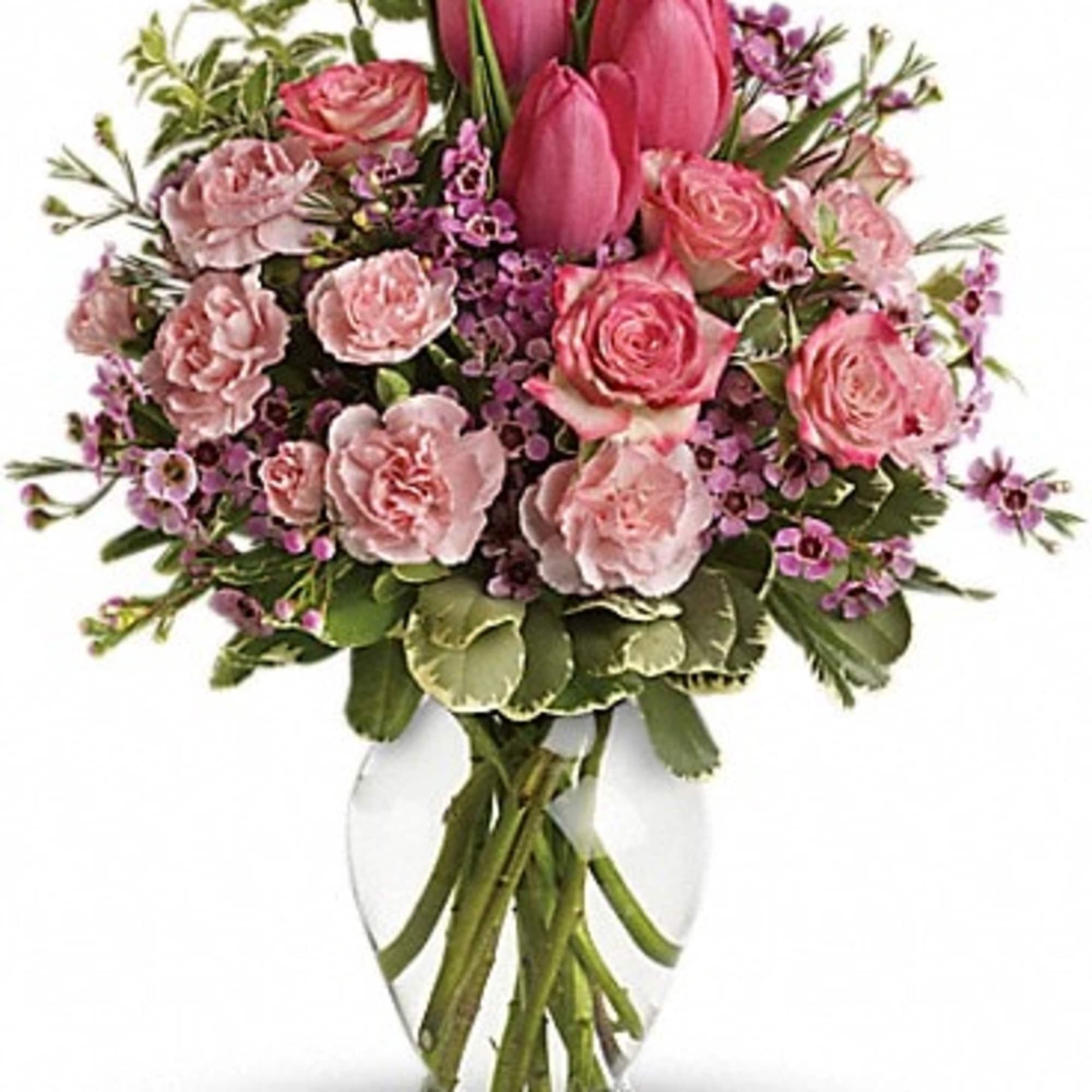 Spring into pink! Delicate roses, tulips and carnations fill a graceful vase