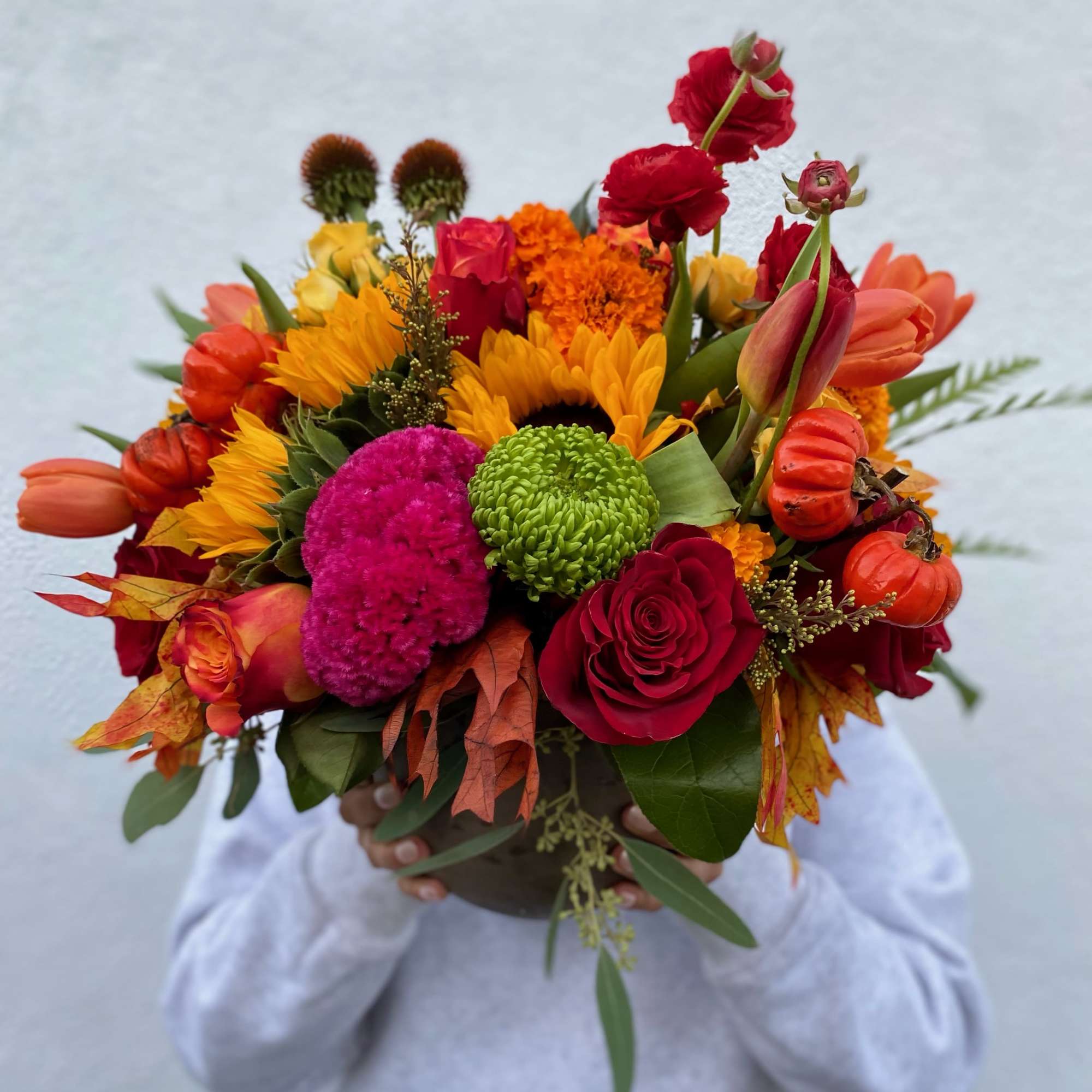 This stunning arrangement includes a variety of fall flowers, marigolds, sunflowers, coxcomb