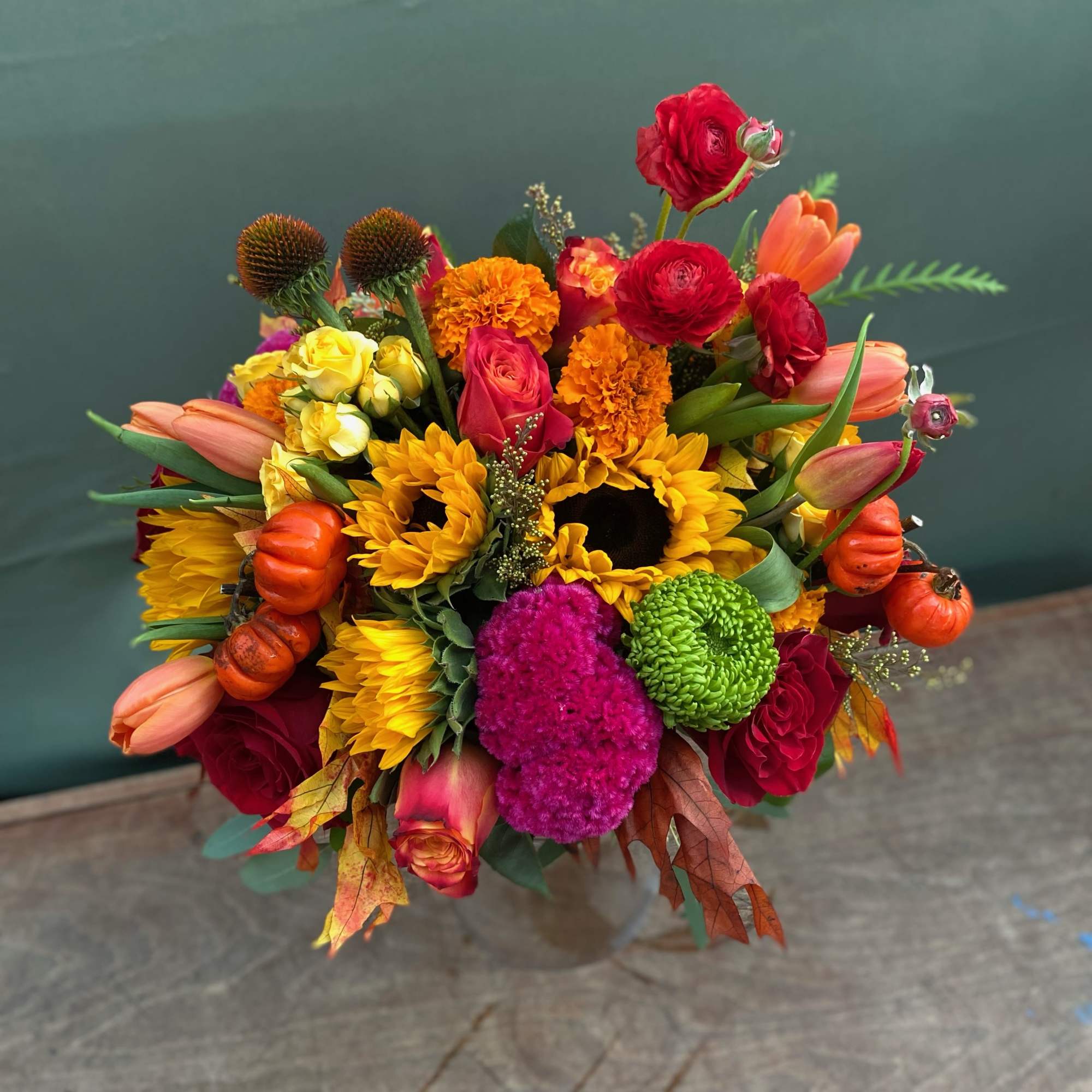 This stunning arrangement includes a variety of fall flowers, marigolds, sunflowers, coxcomb