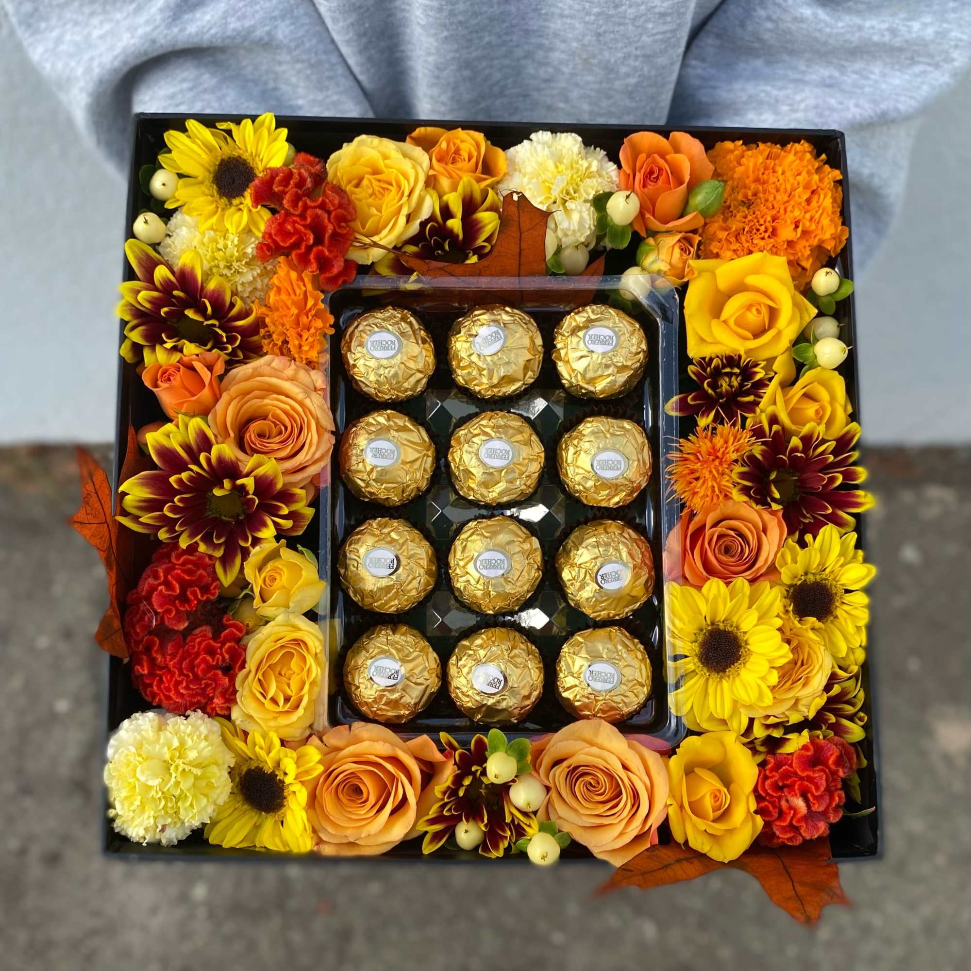 This arrangement includes variety of fall color flowers with ferrero chocolates. 