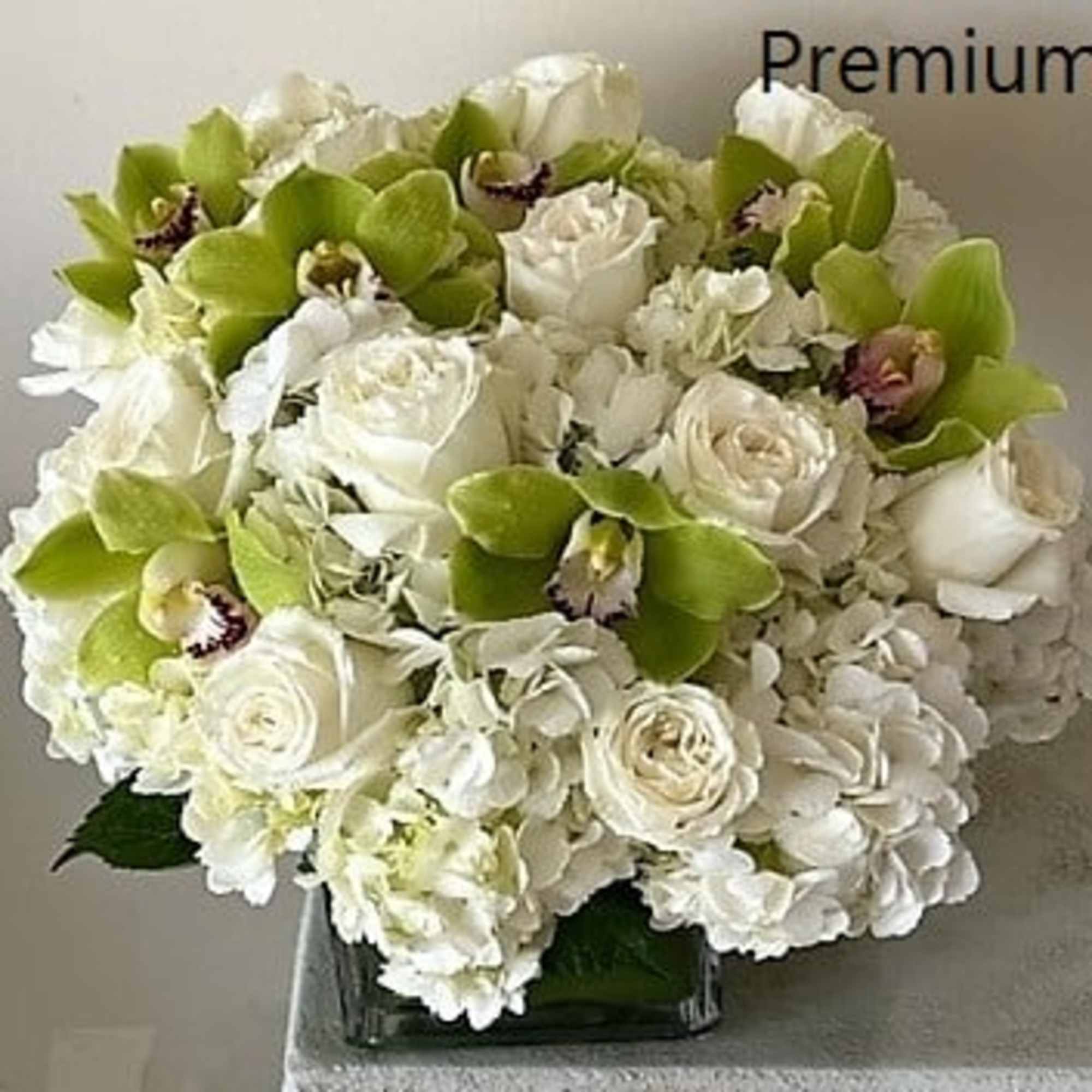 White Roses with White Hydrangeas mixed with green Cymbidium Orchid flowers. Arranged