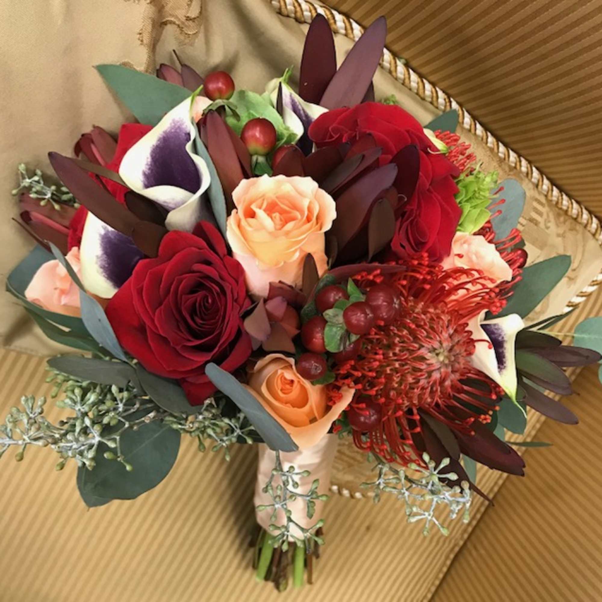 Picasso mini calla lilies, red roses, cushion proteas, peach roses, hypericum, leucadendrom