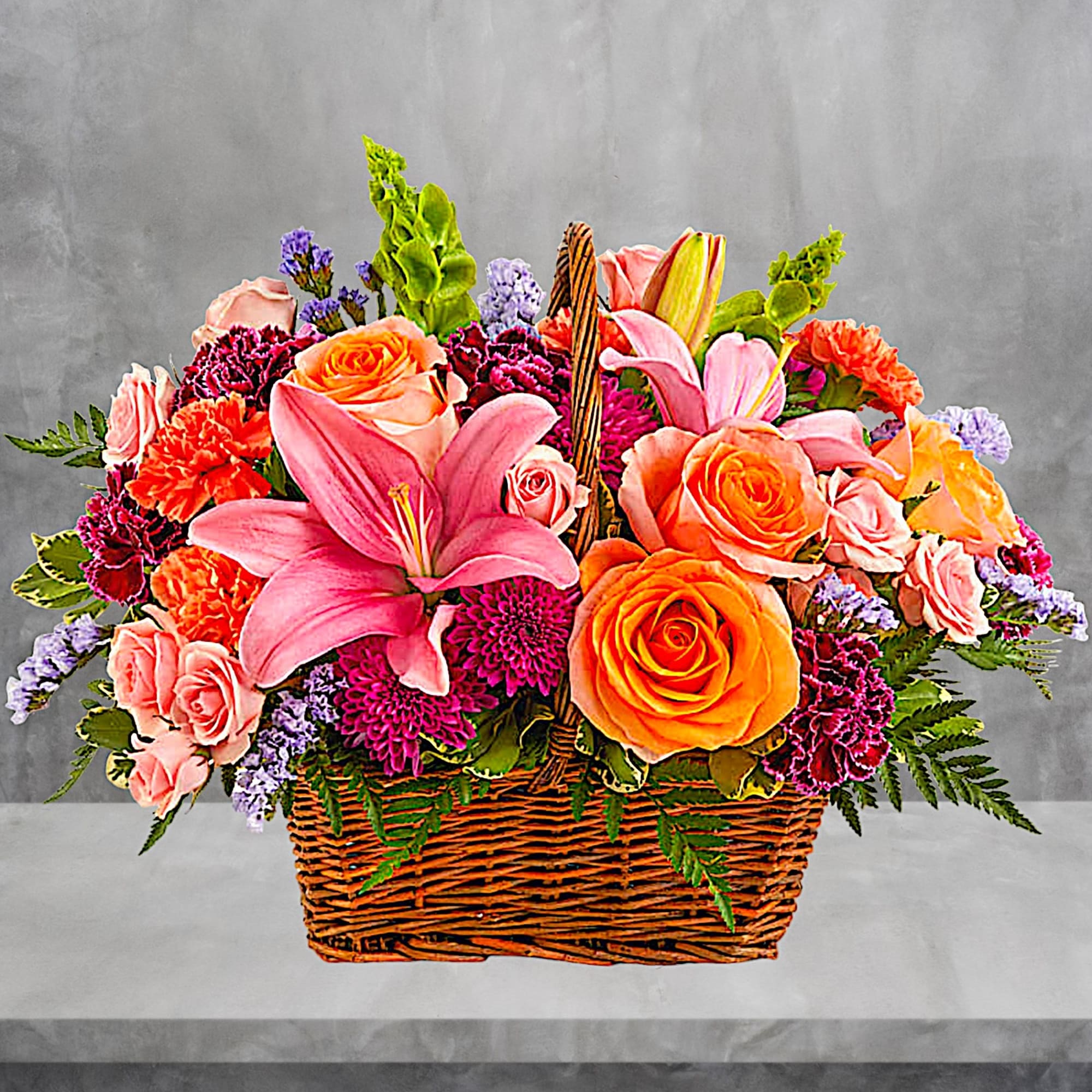 Like an island sunrise, this basket of orange and pink blooms is