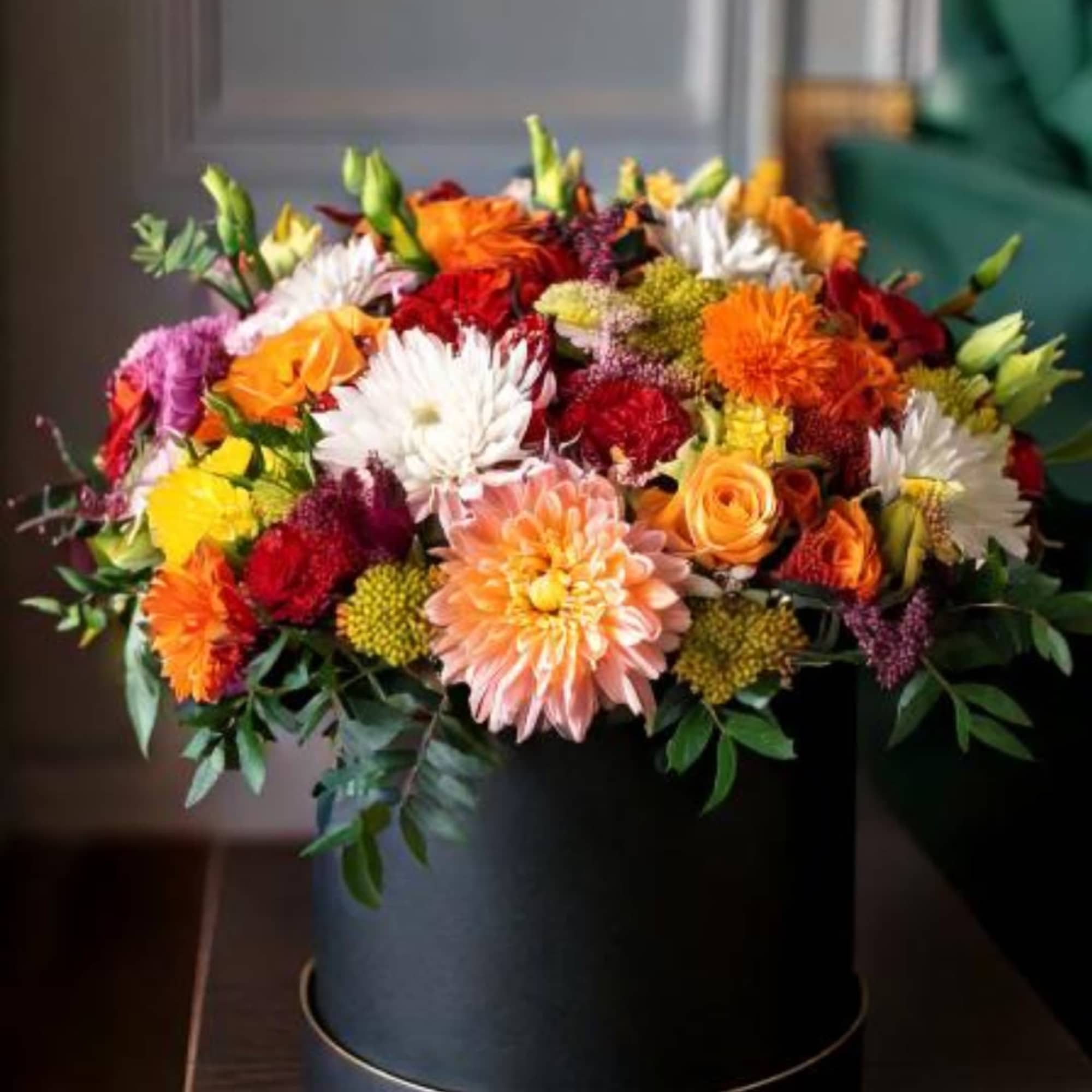 This floral arrangement showcases a vibrant mix of dahlias, chrysanthemums, and roses
