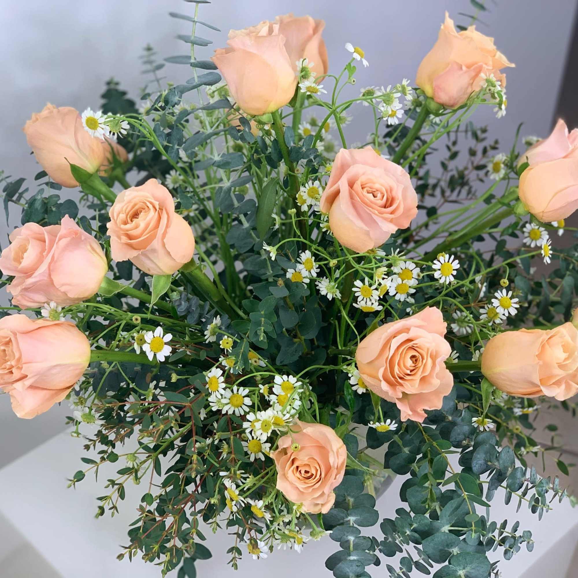 Peach premium roses in a round shape vase with a variety of