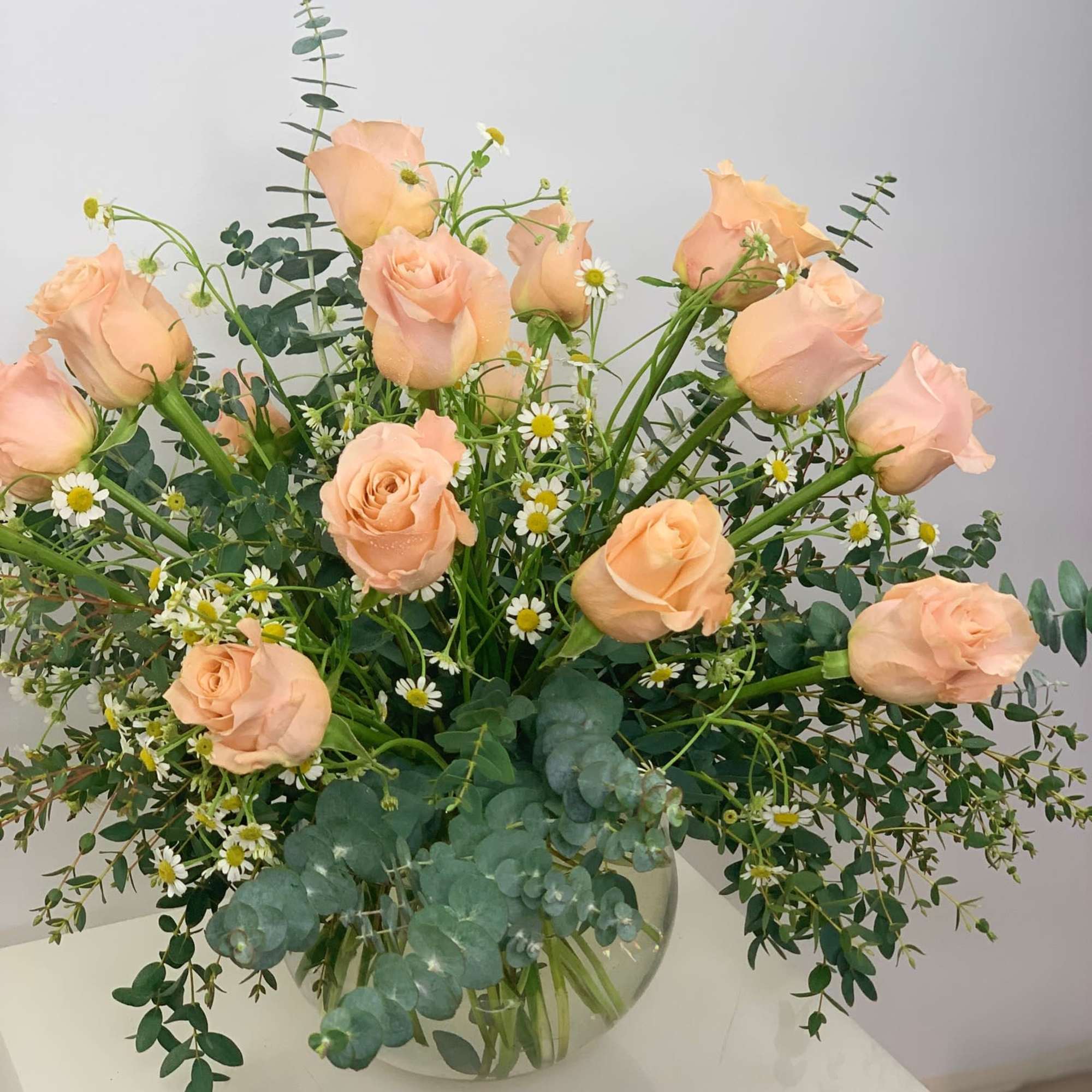 Peach premium roses in a round shape vase with a variety of