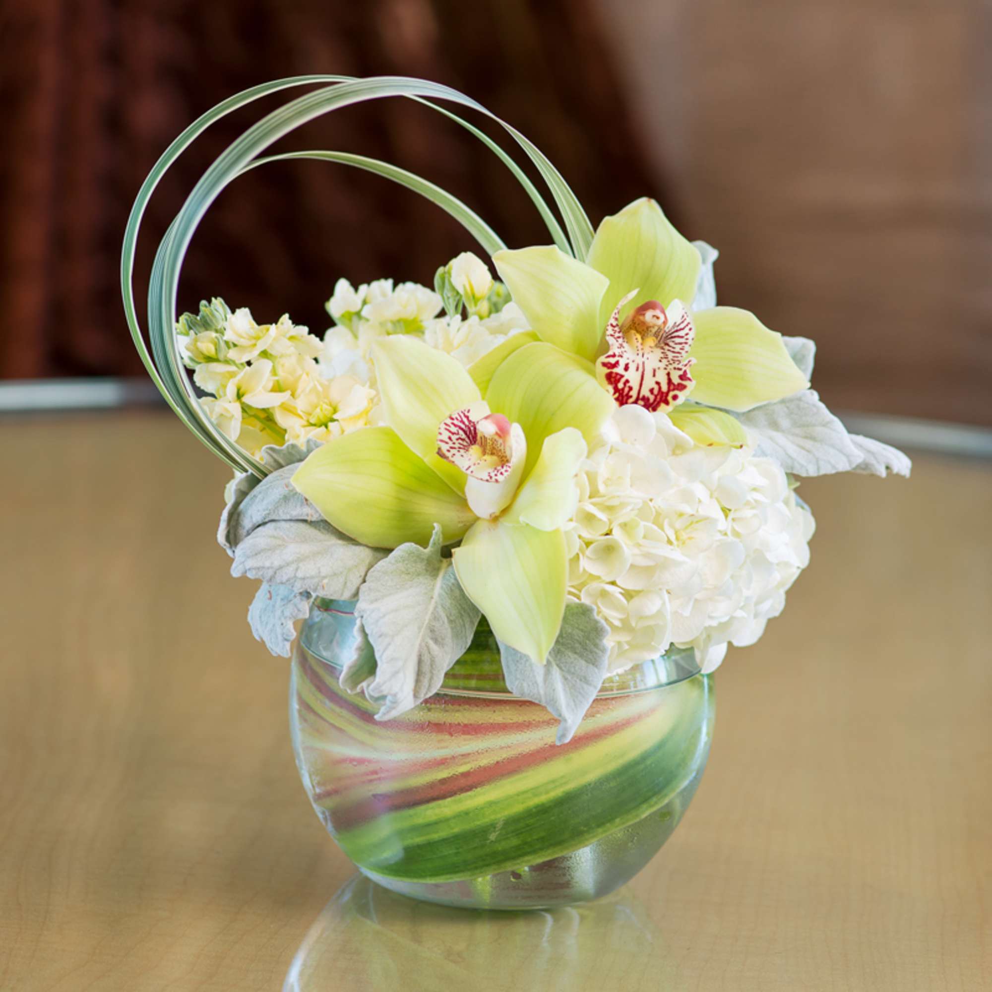Simple and elegantly arranged cymbidium orchids and hydrangeas accented with dusty miller