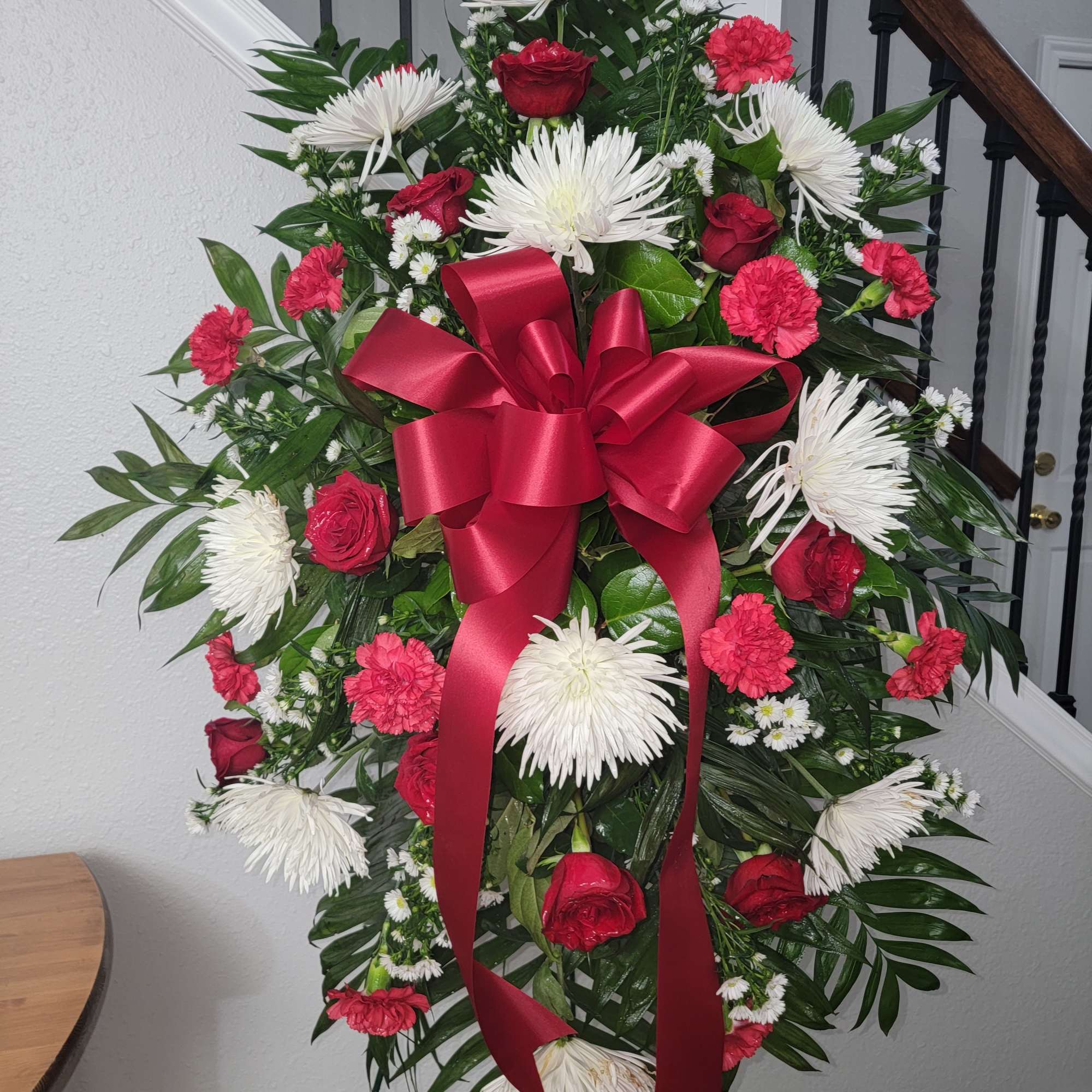 Classic red and white easel display featuring rose &amp; carnations. Approximate size