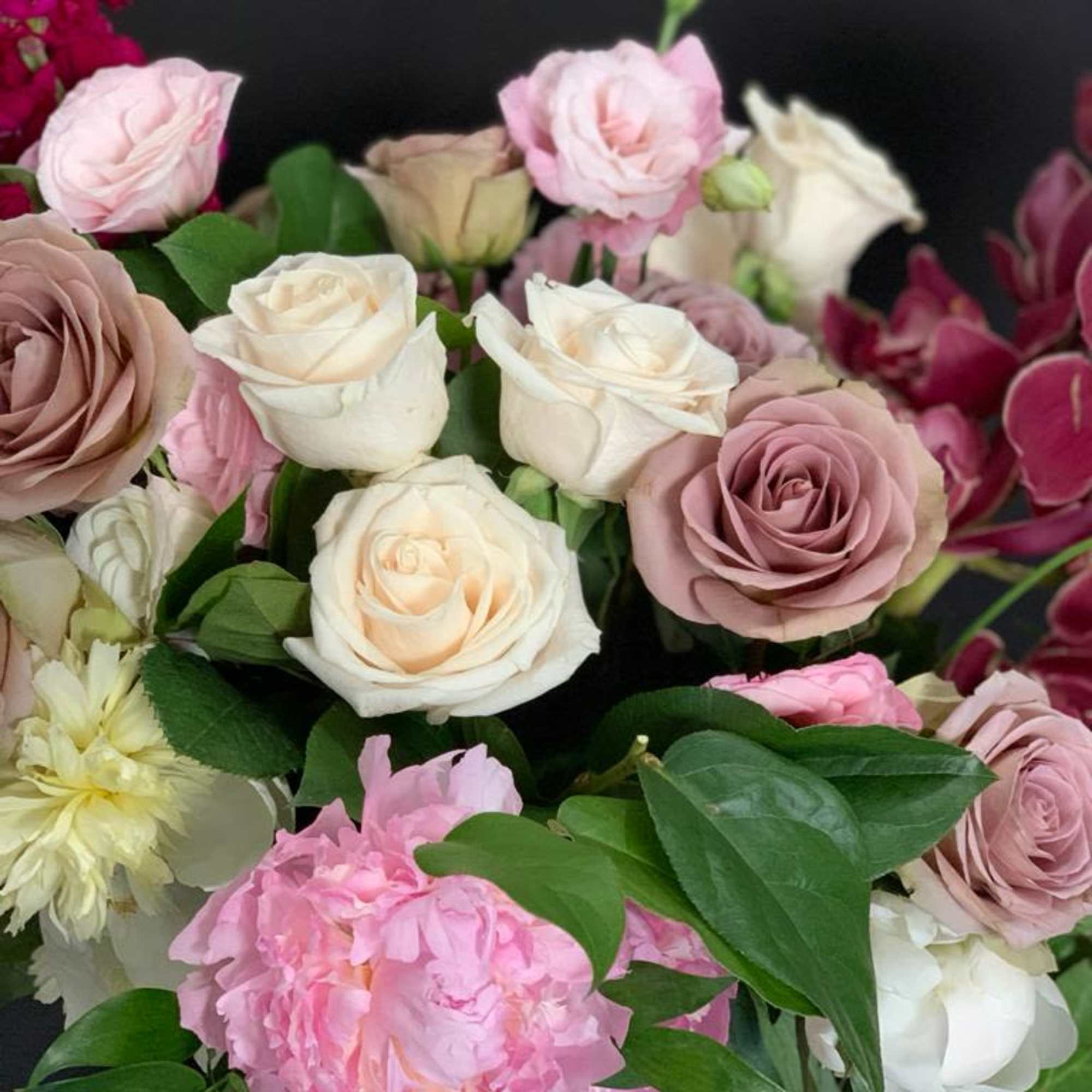 Stunning organic shape arrangement featuring beautiful roses, peonies, stock, and cymbidium orchids.