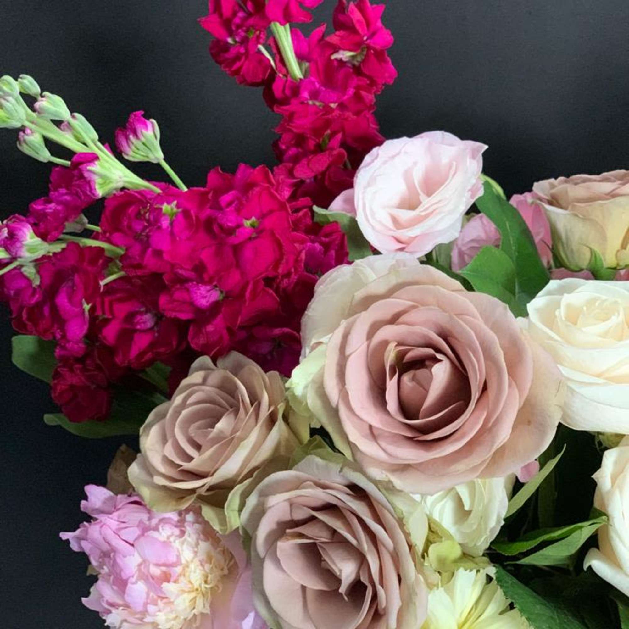 Stunning organic shape arrangement featuring beautiful roses, peonies, stock, and cymbidium orchids.