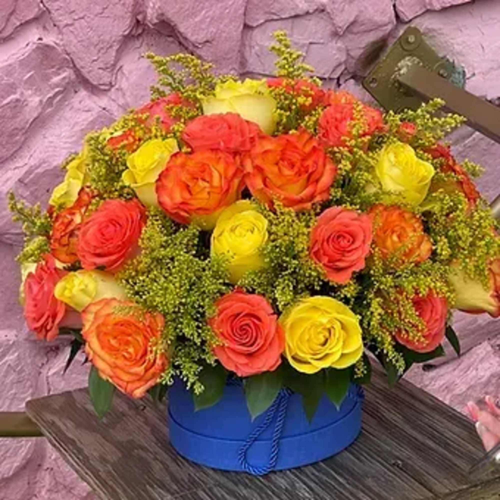 This exquisite floral arrangement of orange and yellow roses in a stylish