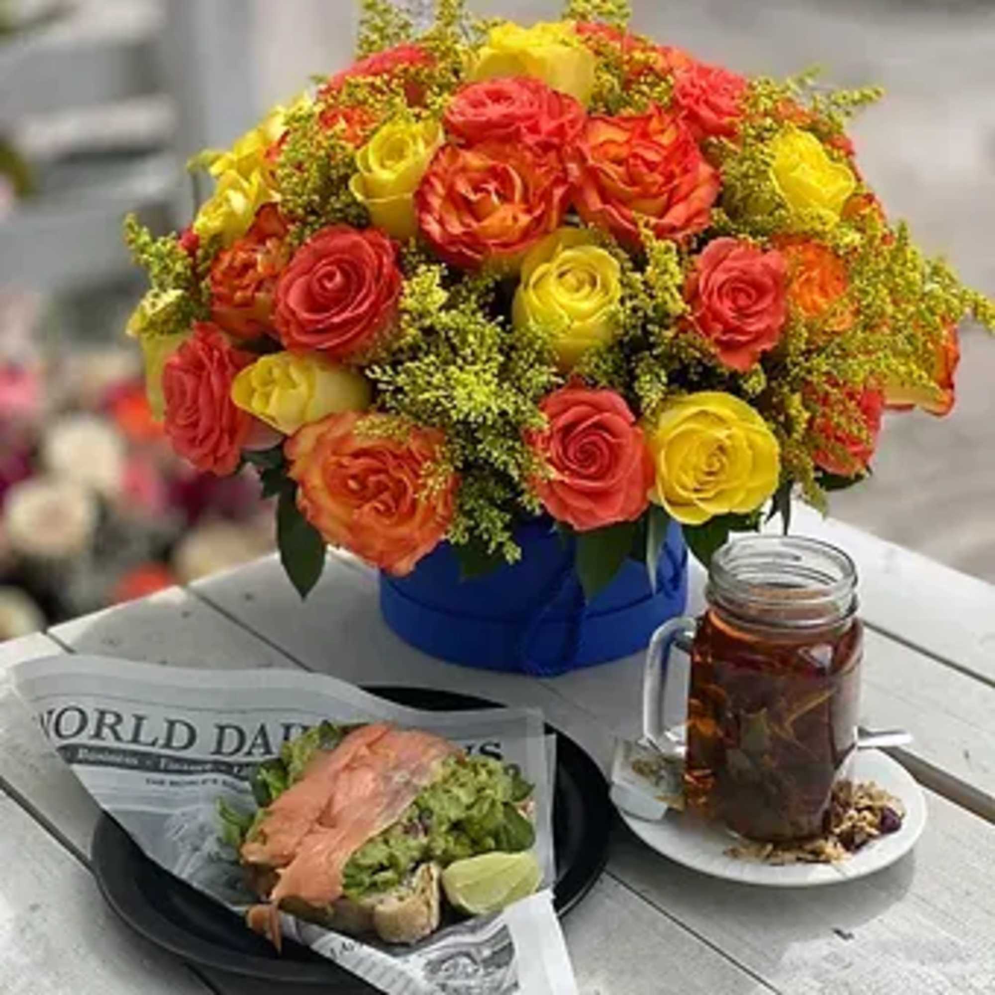 This exquisite floral arrangement of orange and yellow roses in a stylish