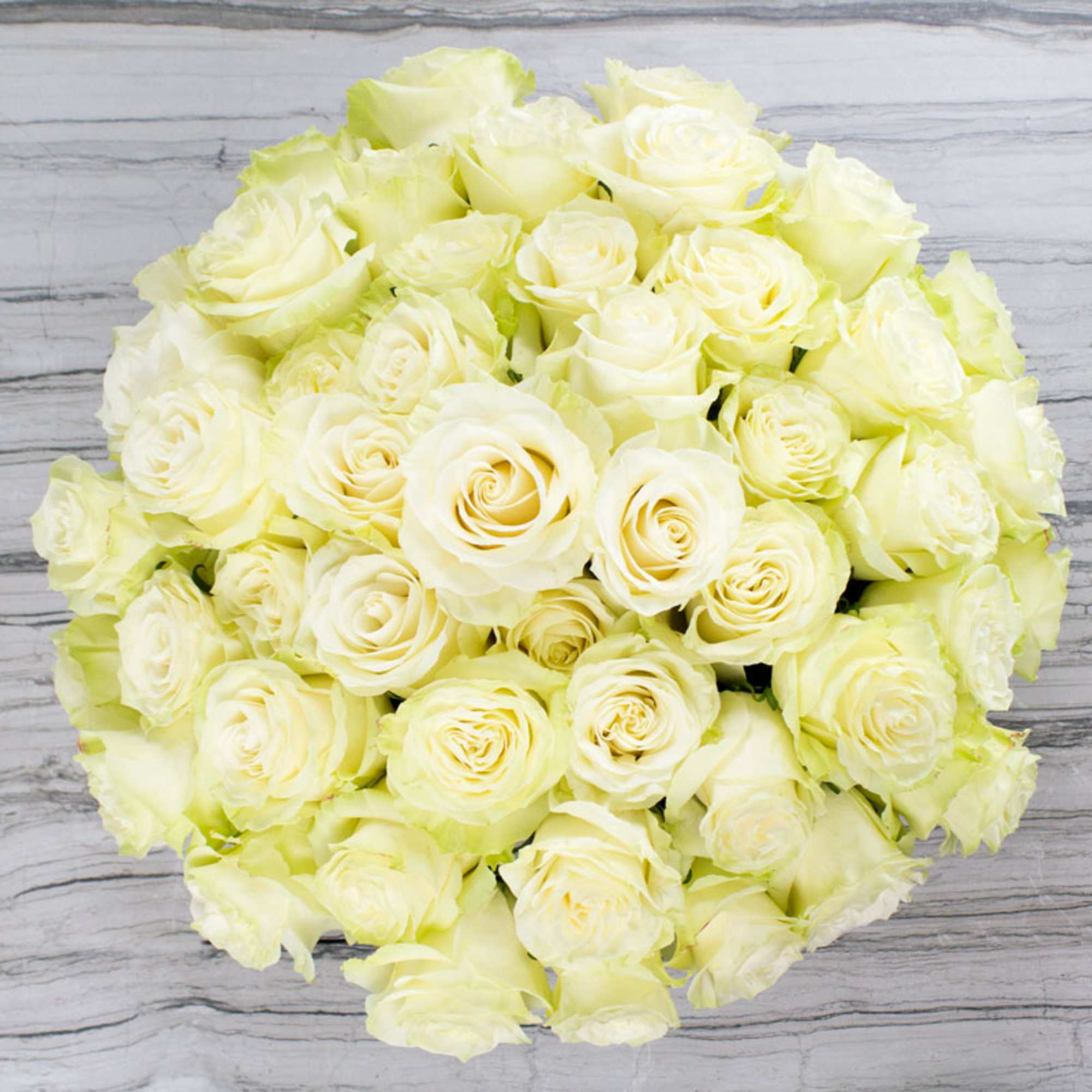 Top view of a dense round bouquet of cream and ivory roses