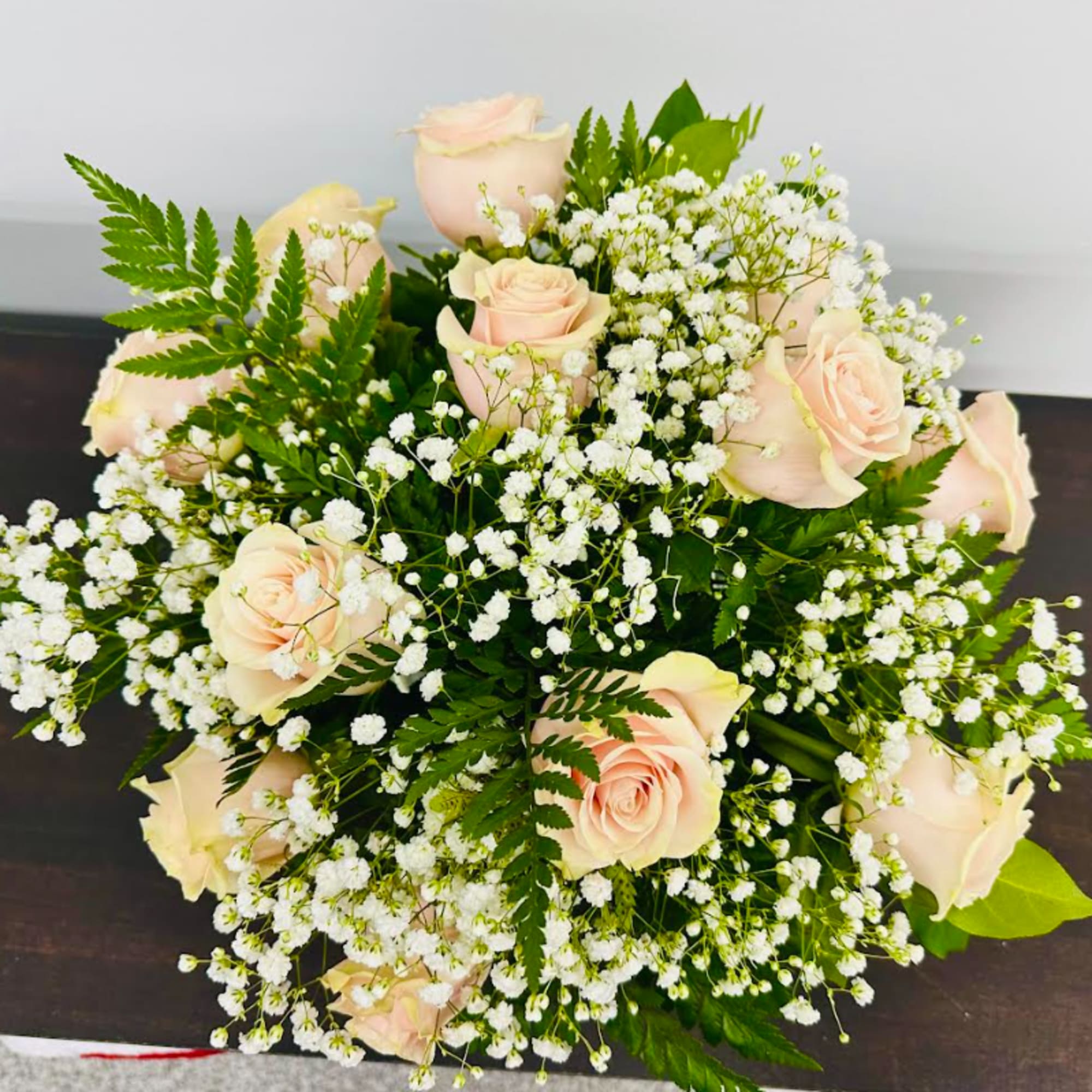 A delicate bowl arrangement of light pink roses with babies breath for