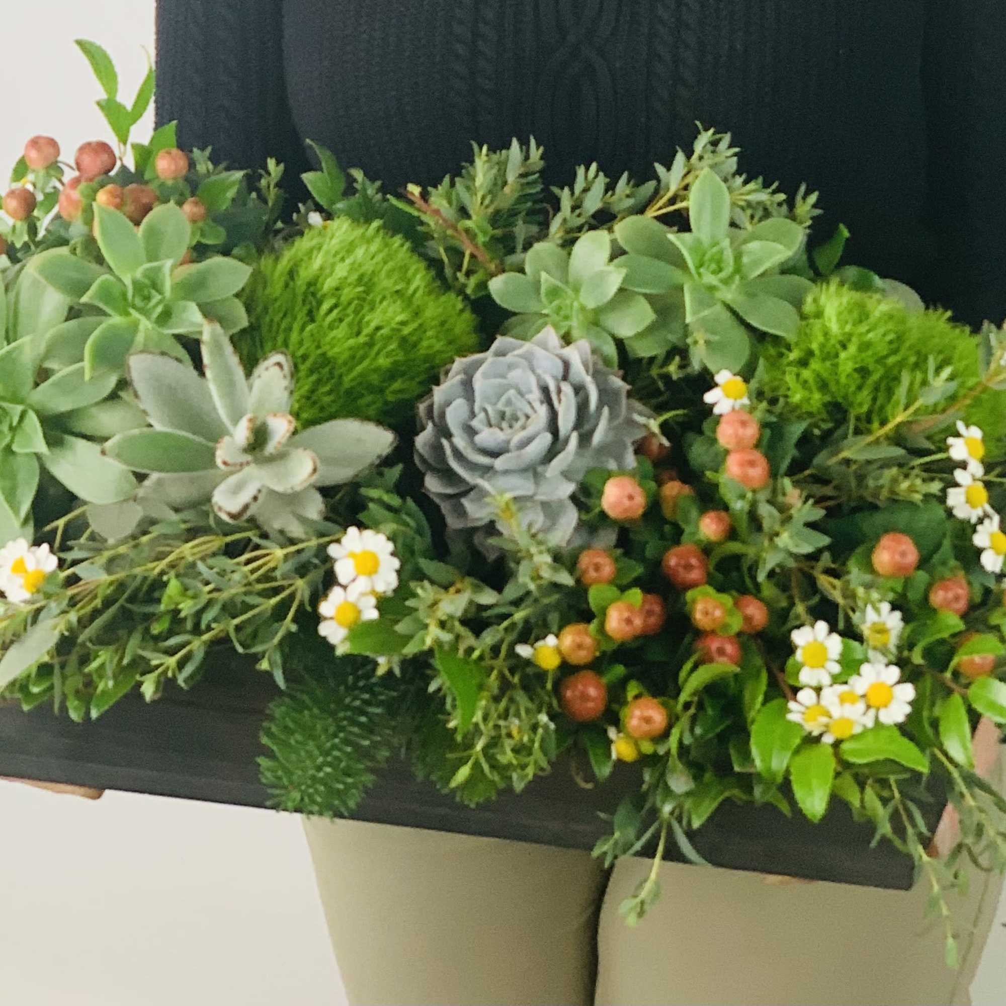 This long lasting centerpiece features a variety of greenery, natural flowers, succulents