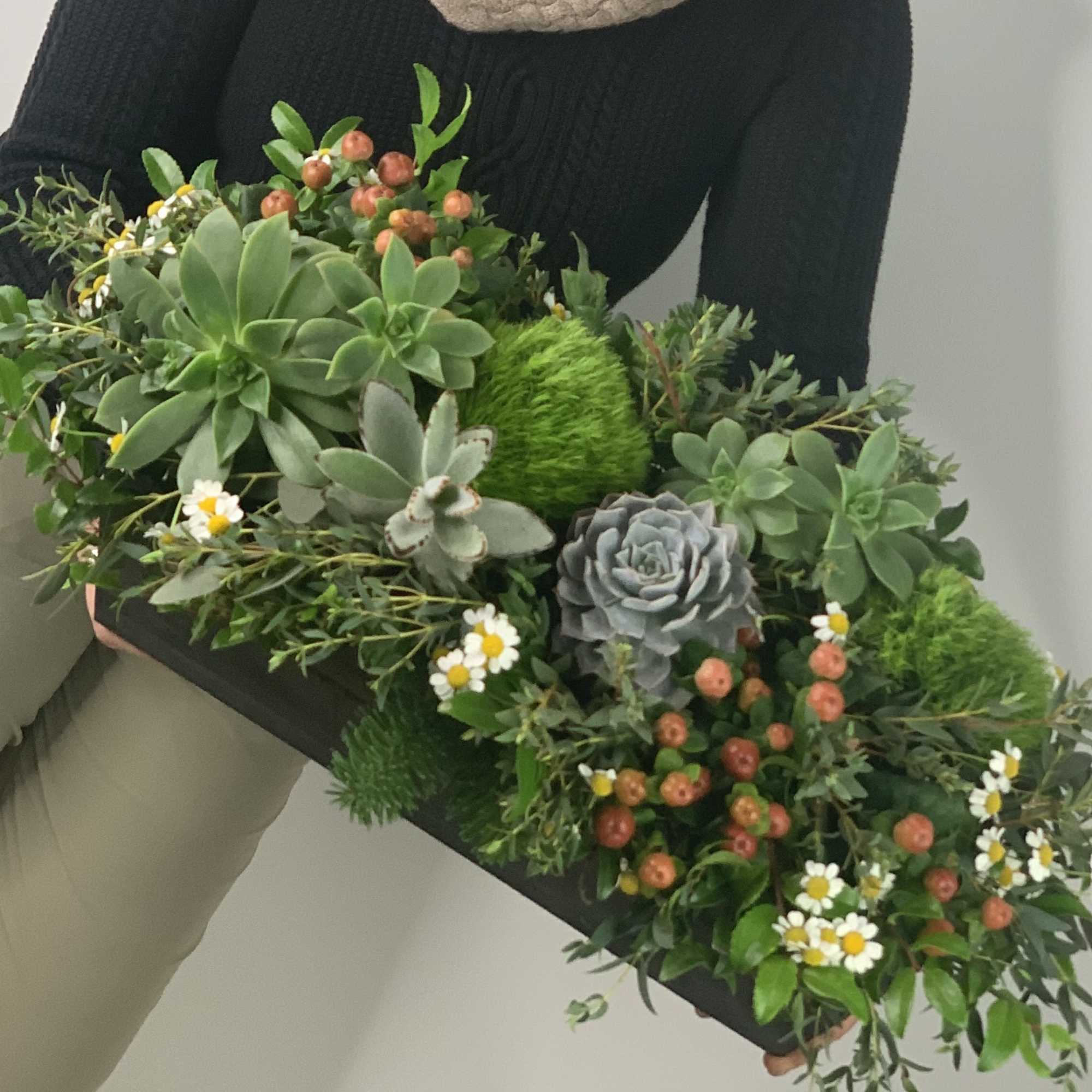 This long lasting centerpiece features a variety of greenery, natural flowers, succulents